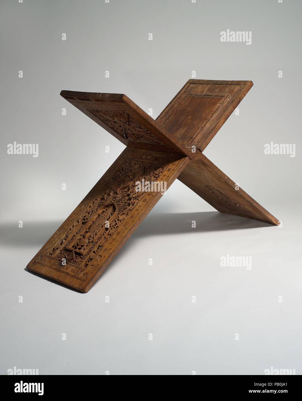 Stand for a Qur'an Manuscript. Dimensions: W. (when closed) 16 1/8 in. (41 cm)  H. (when closed) 51 1/4 in. (130.2 cm)  Dimensions when open: H. 45 in. (114.3 cm)  W. 50 in. (127 cm)  D. 16 1/2 in. (41.9 cm). Maker: Zain(?) Hasan Sulaiman Isfahani. Date: dated A.H. 761/A.D. 1360.  Three layers of superb carving combining vegetal motifs and calligraphic inscriptions cover the surface of this Qur'an stand. The inscriptions include decorative arrangements of the words Allah, 'Ali, and Muhammad, and blessings upon the Prophet and the Twelve Imams. In addition, they provide us with the information  Stock Photo