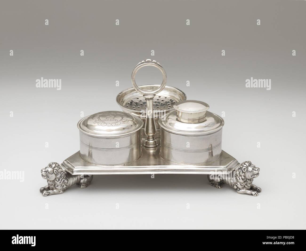 Inkstand. Culture: American. Dimensions: Overall: 4 1/8 x 6 1/2 in. (10.5 x 16.5 cm); 23 oz. 14 dwt. (736.7 g)  Glass ink pot with silver cover: 1 3/4 x 2 1/4 in. (4.4 x 5.7 cm); 4 oz. 12 dwt. (143.3 g)  Pounce pot: 1 1/8 x 2 5/8 in. (2.9 x 6.7 cm); 2 oz. 10 dwt. (78.2 g)  Wafer pot cover: 9/16 x 2 5/16 in. (1.4 x 5.9 cm); 1 oz. 2 dwt. (34.5 g)  Stand and attached parts: 15 oz. 9 dwt. (480.7 g). Maker: John Coney (1655/56-1722). Date: 1710-20.  This rare triangular inkstand on cast lion's feet belonged to the colonial governor Jonathan Belcher. Museum: Metropolitan Museum of Art, New York, USA Stock Photo