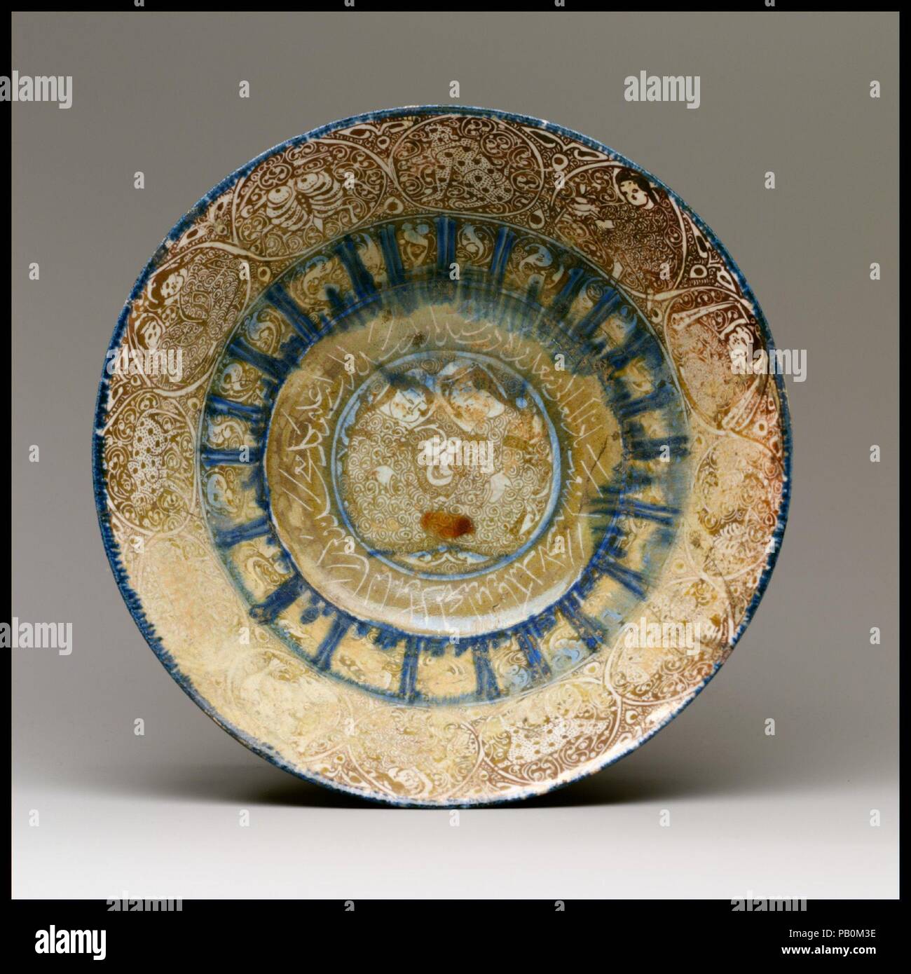 Bowl. Dimensions: Ht. 3 3/4 in. (9.5 cm)  Lip diameter: 8 1/16 in. (20.5 cm). Date: 13th century.  This bowl combines the most distinctive features of lusterware produced in Kashan: moon-faced figures; poetry in <i>naskhi</i> calligraphy; and a covering of spiral marks that fill the areas between the decorative motifs. In addition, the outermost decorative band includes medallions with all twelve signs of the Zodiac. Capricorn (<i>al-jady</i>, 'the kid'), is depicted as a small goat in profile. Like the other Zodiac signs that are represented as animals, such as Aries and Taurus, when shown wi Stock Photo
