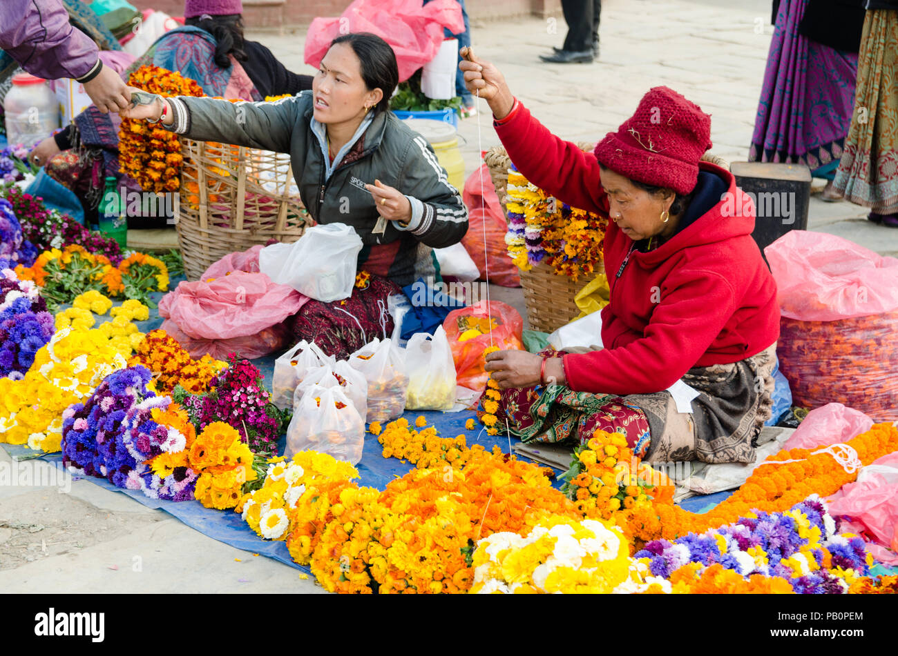 Local Nepali women selling flowers for offering at the base of the steps leading to Swayambhunath or Monkey Temple, Kathmandu, Nepal Stock Photo