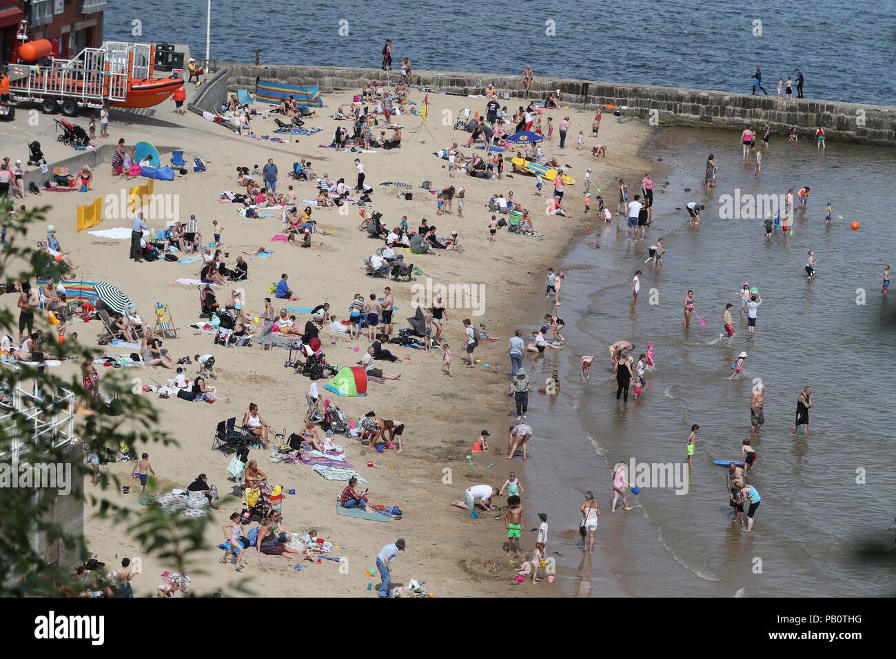 People enjoying the heatwave today on Cullercoats beach on North Tyneside as the hot weather continues across the UK, marking the driest start to a summer since modern records began in 1961. Stock Photo