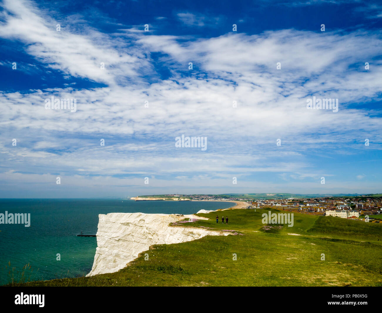 People walking on Seaford Head, East Sussex, UK, with the towns of Seaford and Newhaven in the background on a sunny spring day. Stock Photo