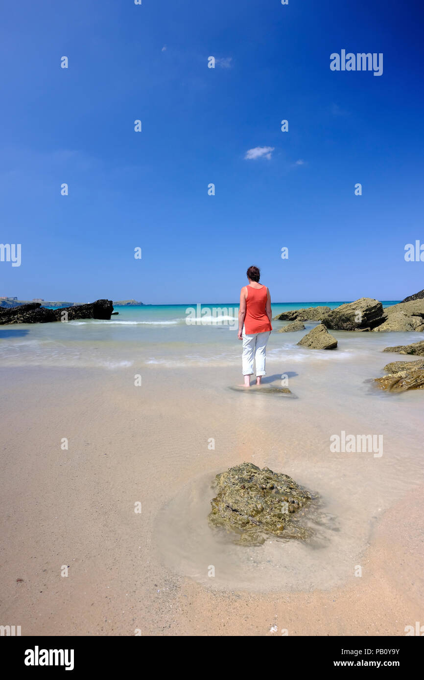 Woman standing in shallow water on a beautiful beach in Cornwall Stock Photo