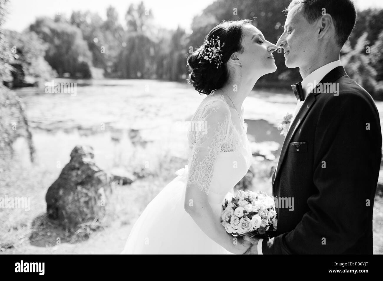 Wedding couple walking and looking into each other's eyes on the river bank. Black and white photo. Stock Photo
