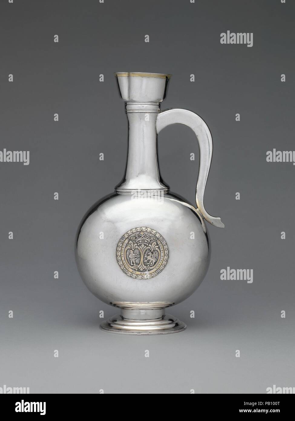 Wine decanter. Culture: Hungarian, Kolozsvár. Dimensions: Overall: 12 13/16 x 4 7/16 in. (32.5 x 11.2 cm). Maker: Johannes Szakáll (active 1748-72). Date: 1779.  The goldsmith designed this innovative, even forward-looking, vessel to serve mulled wine, a popular spiced drink. The beverage was prepared by placing spices on the slightly funnel-shaped filter of the decanter and then pouring hot wine over them. The inscriptions on the medallions applied to either side of the flattened round body may refer to two weddings. One inscription, G. BETHLEN GERGELY/G. KENDEFFI RACHEL/1779, may mark the un Stock Photo