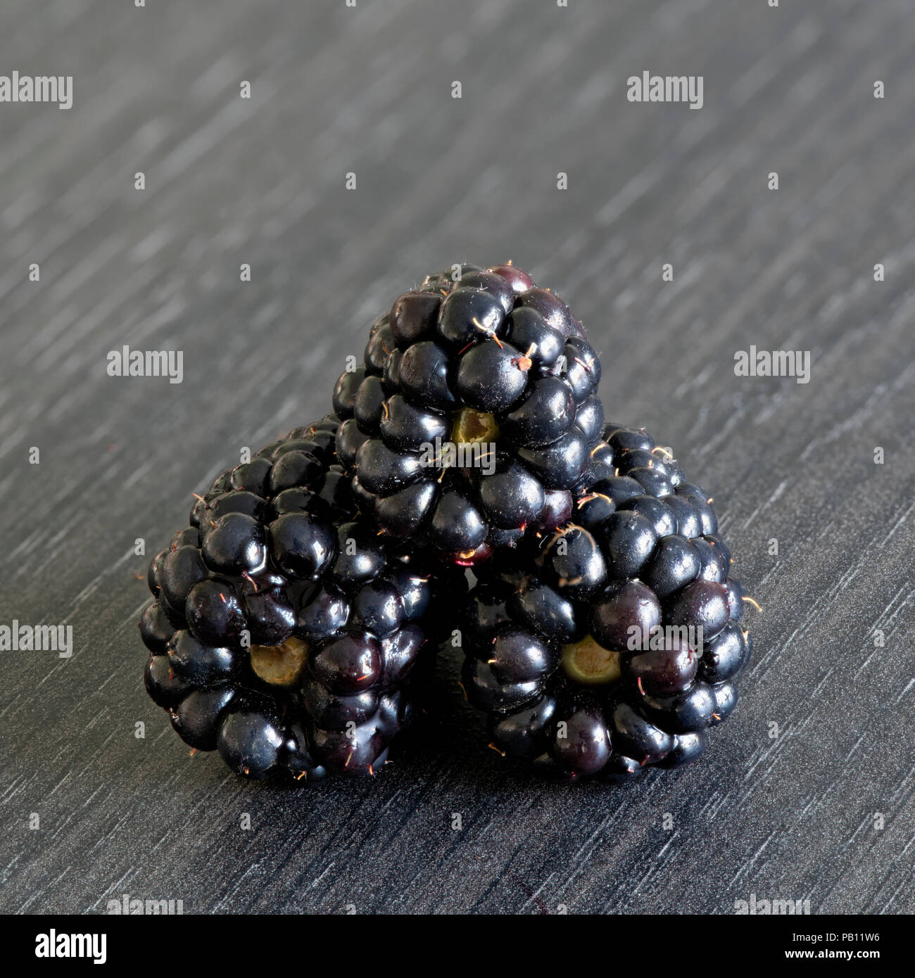 Three  luscious ripe blackberries on a grey kitchen worktop Stock Photo