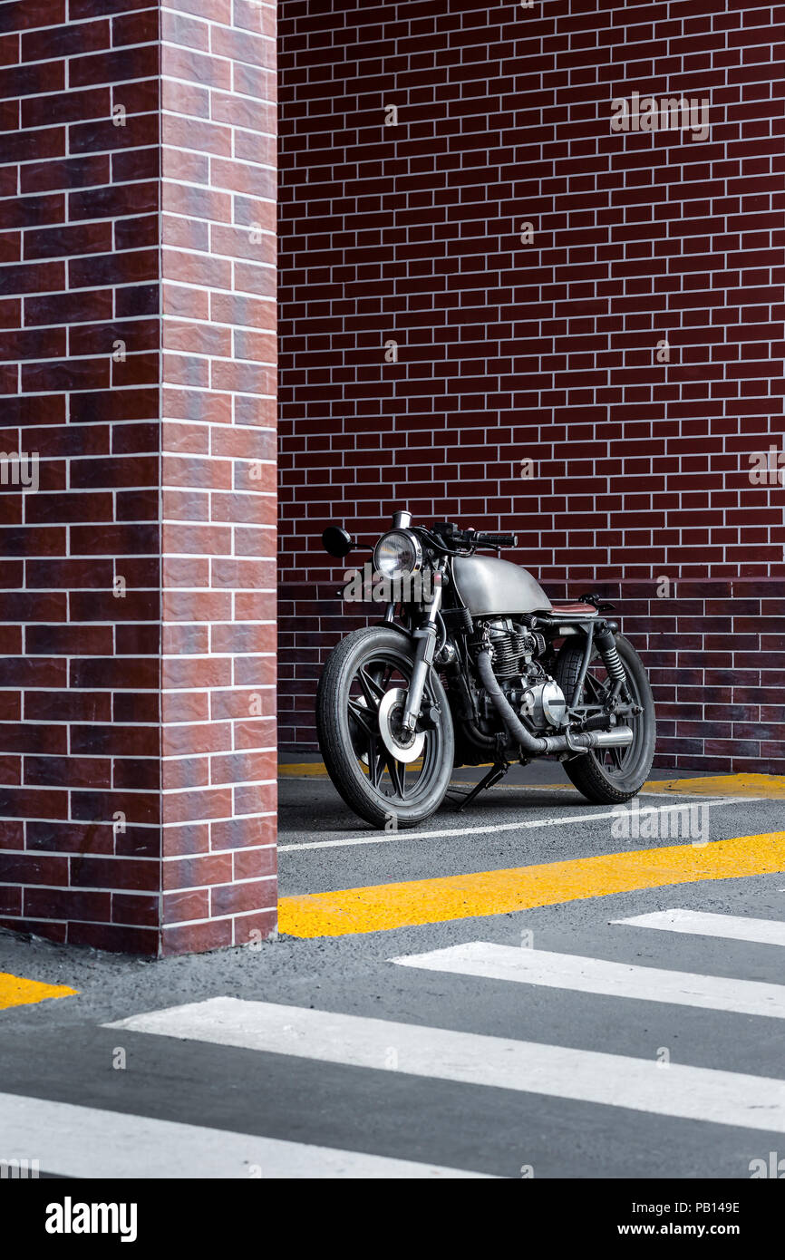 Custom motorcyle parking near brick wall of industrial building. Everything is ready for having fun after hard day in office. Businessman city hipster Stock Photo