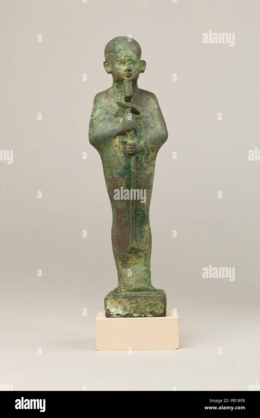 Ptah. Dimensions: H. 17.4 cm (6 7/8 in.); W. 4.7 cm (1 7/8 in.); D. 4.8 cm (1 7/8 in.)  H. (with tang): 19.2 cm (7 9/16 in.). Date: 664-30 B.C..  This statuette depicts Ptah, the chief god of Egypt's capital city Memphis and master craftsman of the gods. He is easy to identify by his tight-fitting cap, straight beard (different from the usual curved divine beard on other gods), and enveloping garment. The garment has a stiff upper edge along the back of the neck, a feature that occurs with some regularity also on Osiris statuettes, but its meaning is unclear. A shallowly carved oval area on hi Stock Photo