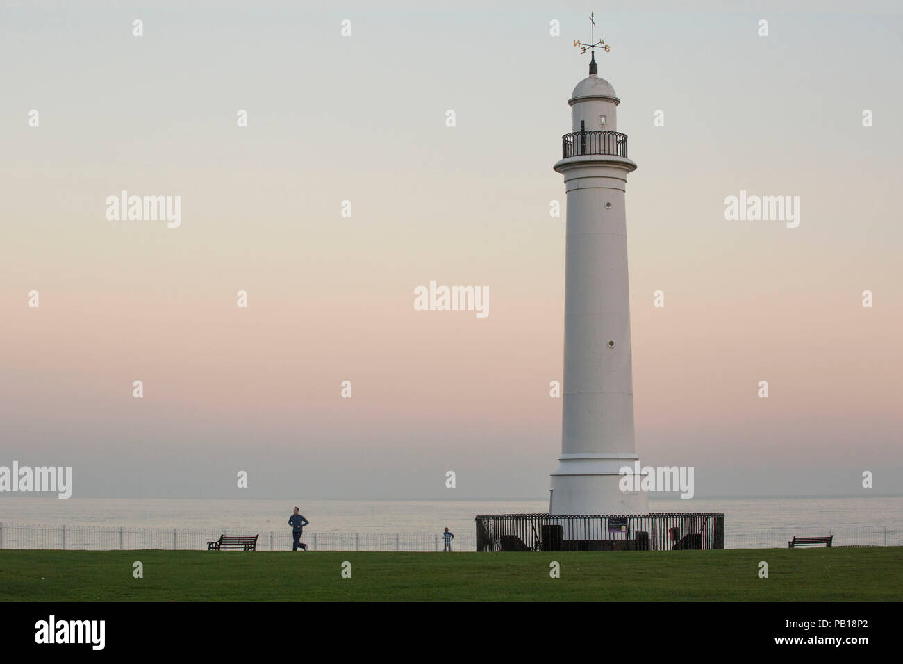 Jogger on Promenade with Lighthouse in Shot, North East Coast. UK Stock Photo