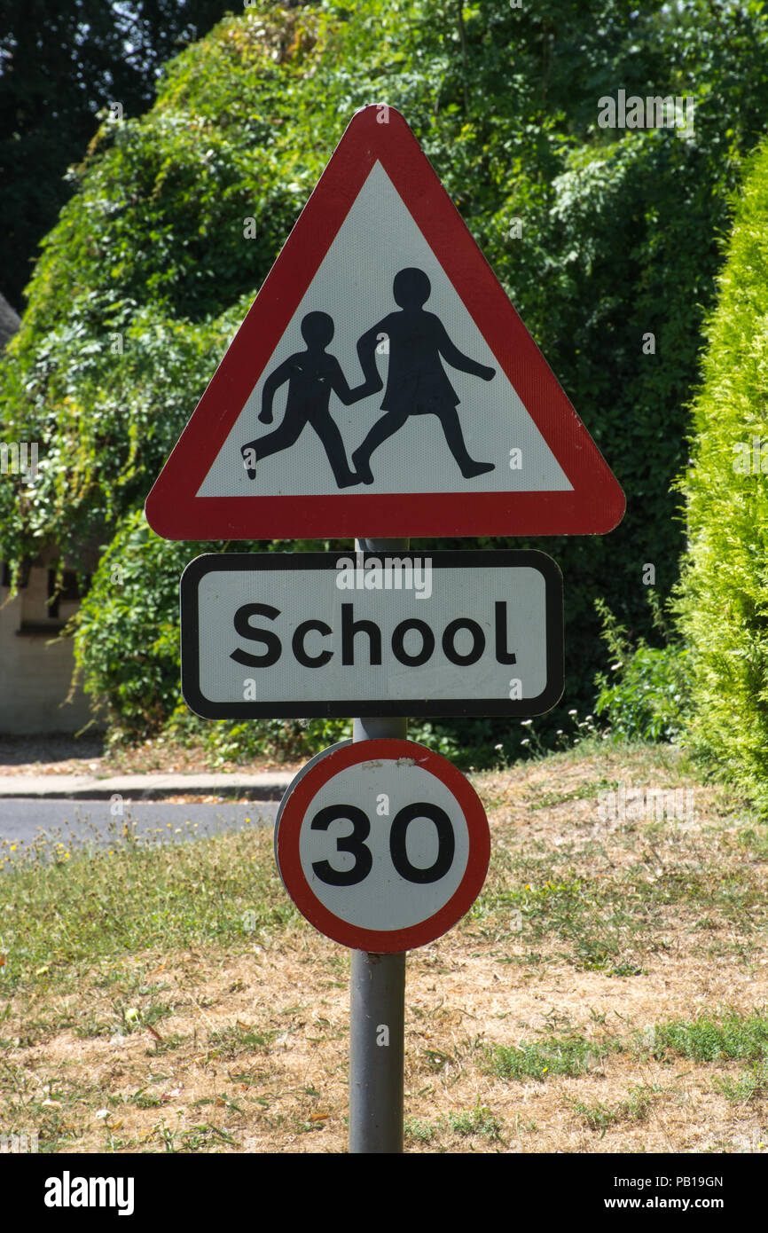 Road sign warning of a school, triangular sign with children, 30 mph speed limit Stock Photo