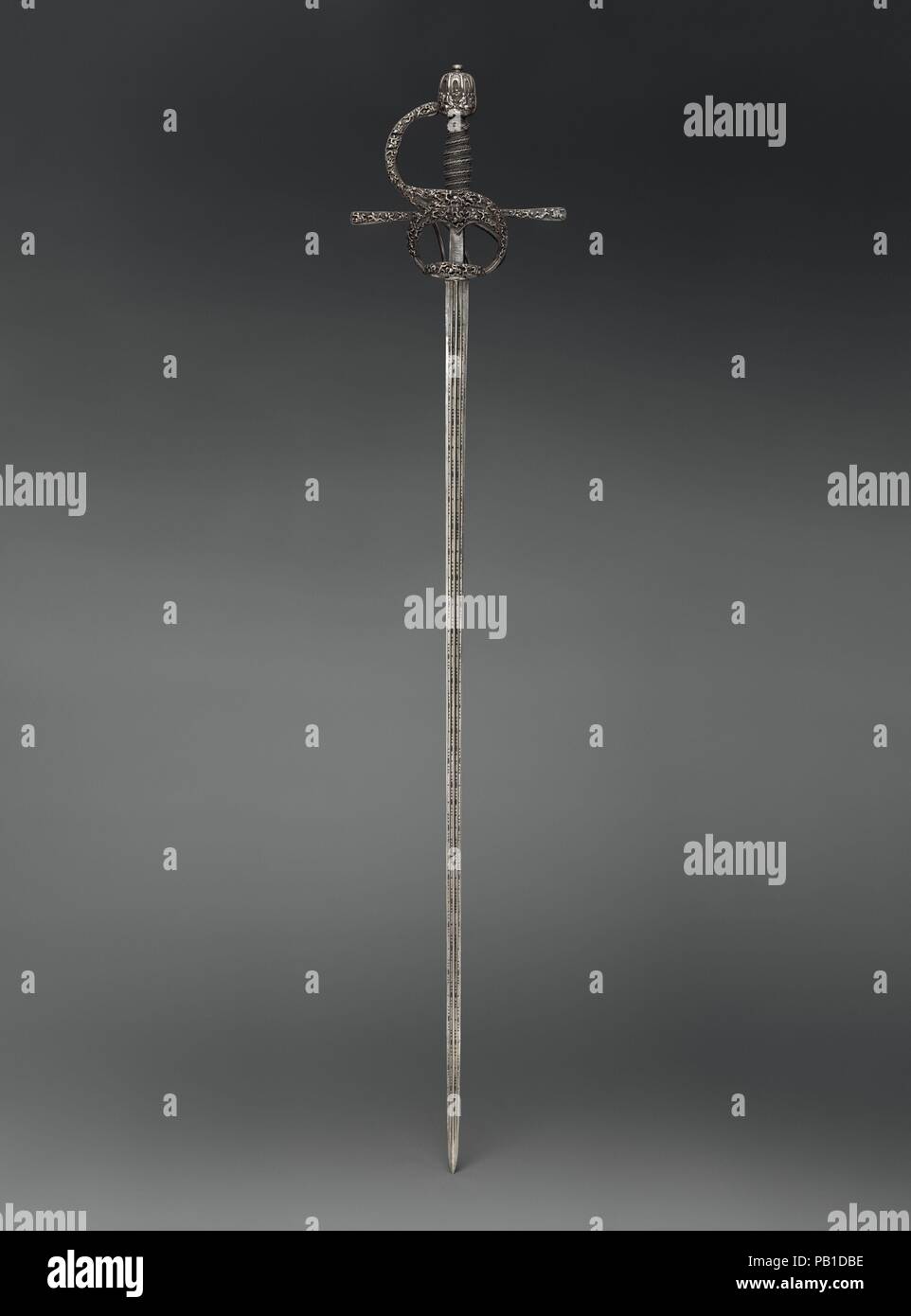 Rapier. Bladesmith: Pietro de Formicano (Italian, Belluno, active ca. 1600). Culture: hilt, Northern European, possibly German; blade, Italian, Belluno. Dimensions: L. 47 1/16 in. (119.5 cm); L. of blade 40 1/2 in. (102.9 cm); W. 9 in. (22.9 cm); Wt. 2 lb. 10 oz (1190 g). Date: ca. 1610-20.  The hilt is of blackened iron and consists of an ovoid pommel surmounted by a flattened button, a knuckle guard, two quillons slightly expanding toward rounded tips, arms of the hilt, and two side rings, the upper one connected to the knuckle guard by a short diagonal branch. The wooden grip of oval sectio Stock Photo