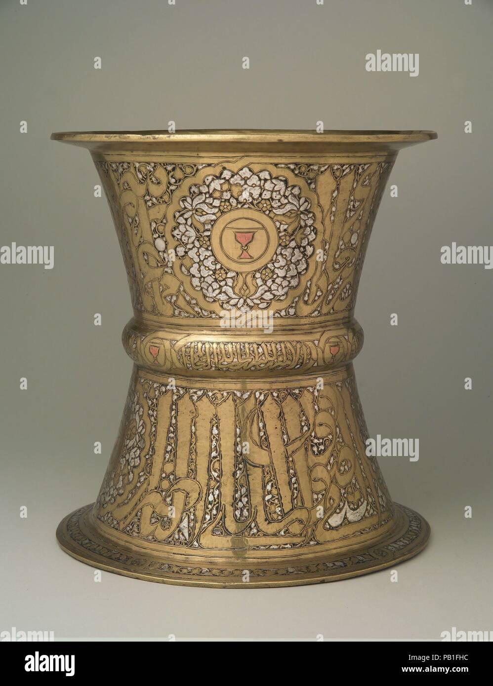 Tray Stand. Dimensions: H. 10 1/4 in. (26.0 cm)  D. 9 5/8 in. (24.4 cm). Date: mid-14th century.  Similar stands were widely employed in the Mamluk period to host large rounded metal trays (such as 91.1.604), on which fruits and other food were displayed.  The cup motif inlaid with copper stands out among the richly decoration of this tray. It was a blazon of the cupbearer, one of the differentiated offices of the court of the Mamluk sultans. The inscription reads Husain, son of Qawsun, who was cupbearer to Muhammad b. Qalawun (al-Malik al-Nasir) (1294-1340/41). Despite having been ousted afte Stock Photo