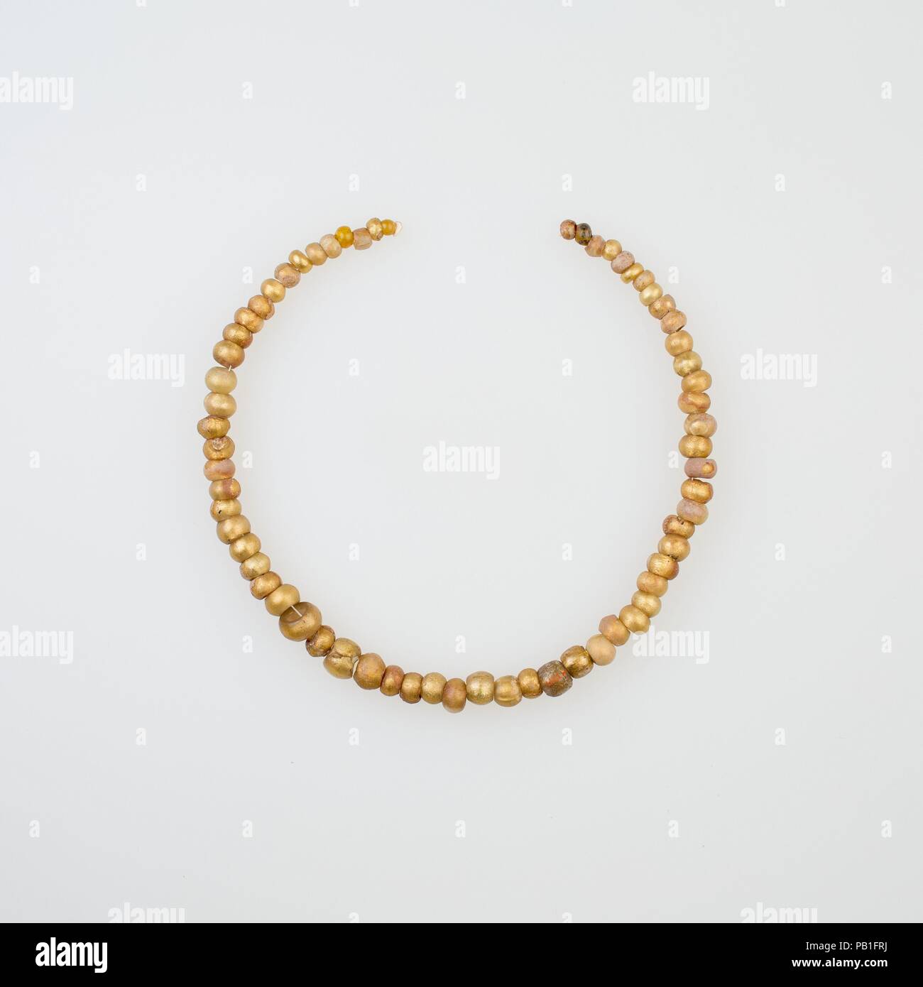 String of 65 Beads. Dimensions: L. 33 cm (13 in.). Date: 2nd century BC-2nd century AD.  Gold glass beads were a Hellenistic development. They were created by combining drawn tubes of colorless glass with gold foil. The earliest examples were finished bead by bead. These are all modern stringings; most ancient stringing patterns are lost as the string decays. Museum: Metropolitan Museum of Art, New York, USA. Stock Photo