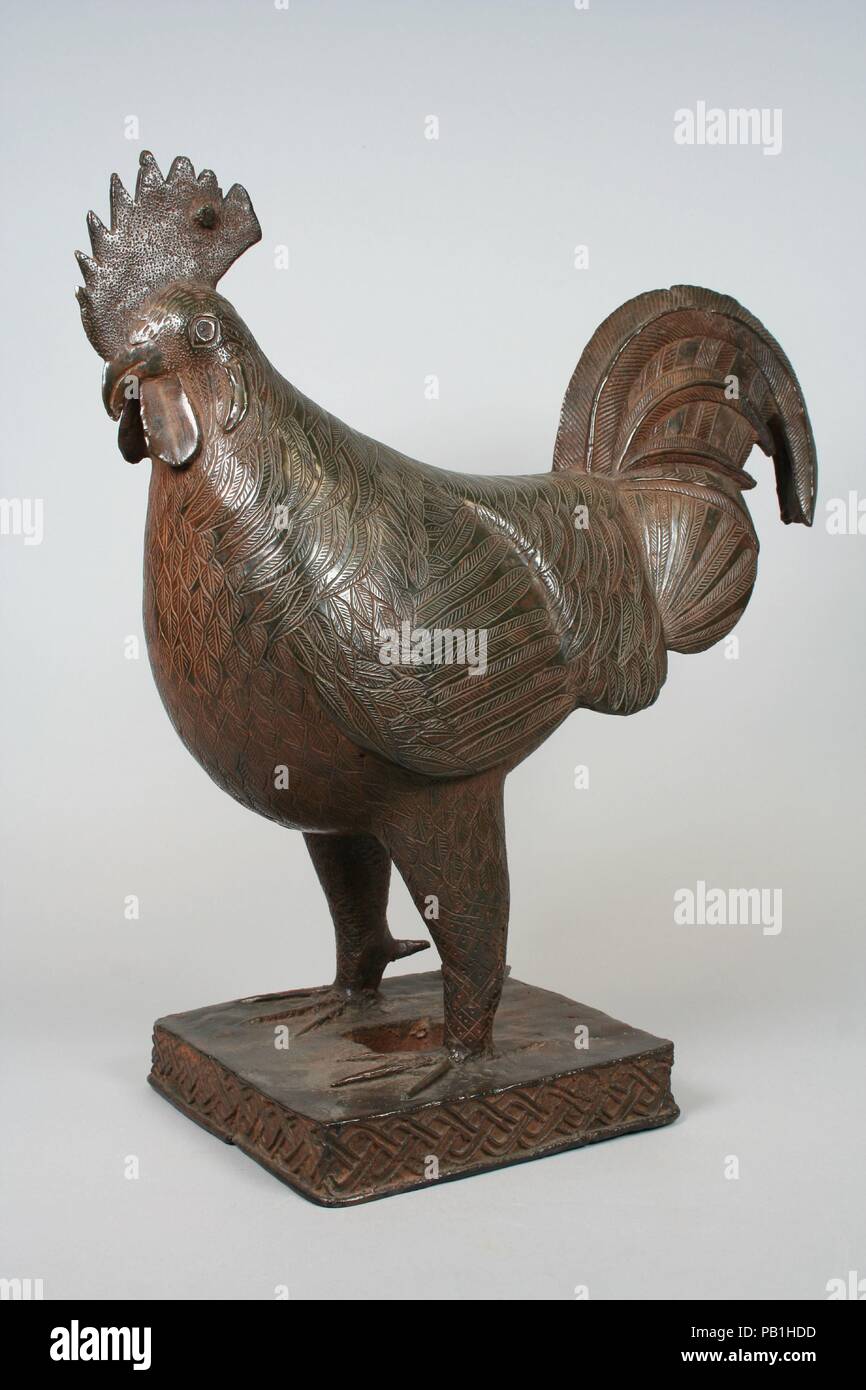 Rooster Figure. Culture: Edo peoples. Dimensions: Overall: 17 7/8 in. (45.4 cm). Date: 18th century.  Brass roosters are placed on ancestral altars commemorating the queen mothers of Benin. They stand for fowl and other animals that are sacrificed during rituals honoring royal ancestors. These explicitly male creatures acknowledge that the queen mother is different from other women and shares many powers and privileges with men. In depicting these birds, Benin brass casters indulge their love of dense overall patterns. Although stylized, these incised designs deftly suggest the rooster's showy Stock Photo