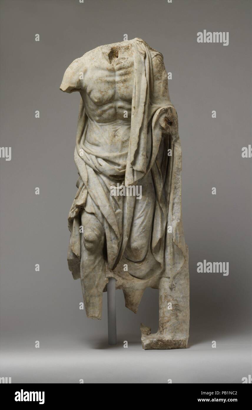 Marble statue of an old fisherman. Culture: Roman. Dimensions: H. 42 in. (106.7 cm). Date: 1st or 2nd century A.D..  Copy of a Greek statue of the late 3rd century B.C.  The effects of hard work and age are powerfully rendered in this representation. A more complete replica in Rome preserves the head and a basket of fish on the left arm, indicating that the stooped figure must be a fisherman. Since his voluminous cloak seems ill-suited to work, he is probably headed for a festival, as is the statue of an aged woman carrying chickens and a basket of fruit, which stands nearby. During the Hellen Stock Photo