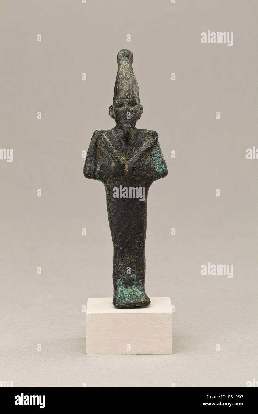 Statuette of Osiris. Dimensions: H. 12.7 cm (5 in.); W. 4 cm (1 9/16 in.); D. 2.3 cm (7/8 in.); H. (with tang): 14.8 cm (5 13/16 in.). Date: 664-30 BC.  Osiris, foremost of the Egyptian funerary gods and ruler of the underworld, stands upright and wears his atef crown. The crown's feathers, now lost, were separately cast and mechanically attached into slots on the sides of the crown. The god's eyes are deep-cut, probably for the addition of gilding or inlay. He is dressed in a close-fitting enveloping garment and he holds the royal crook and flail with his hands poised symmetrically with the f Stock Photo