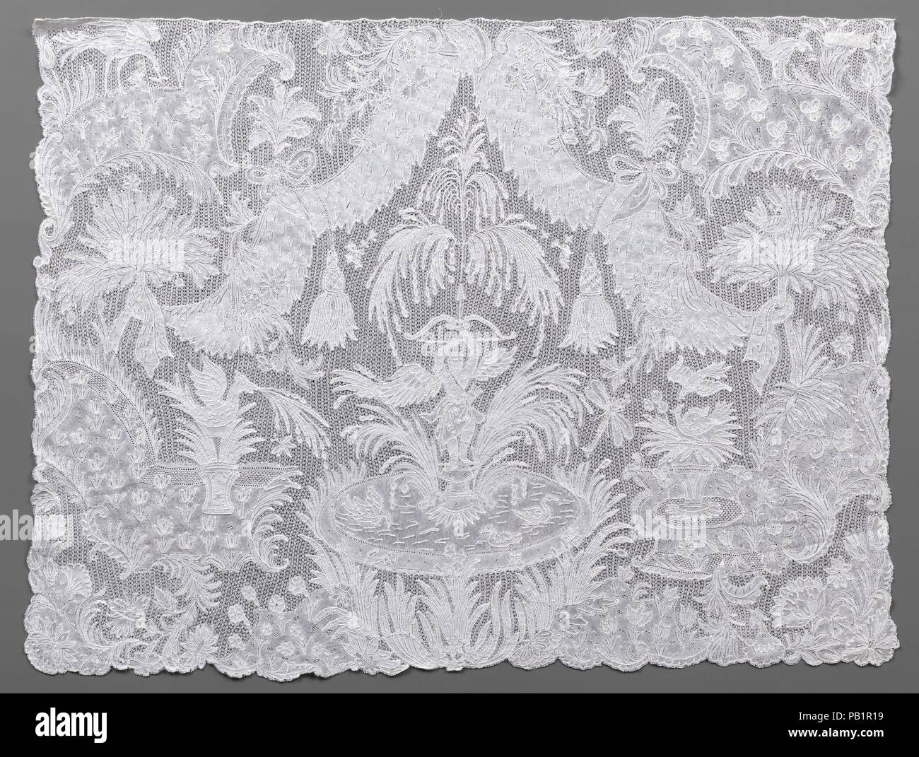 Cravat end. Culture: Flemish, Brussels. Dimensions: Overall (confirmed): 13 × 17 1/4 in. (33 × 43.8 cm). Date: mid-18th century.  Figural lace panels such as this one were items of gentlemen's high-fashion neckwear, meant to be attached to the end of a long, fine fabric cravat. The elaborate imagery, time-consuming to achieve, made the panels extremely expensive accessories. Drawing inspiration from contemporary formal gardens, the design of this example centers on a fountain with water jets that issue from the tip of Amor's raised arrow and fall to fill a basin for swimming birds. Set among t Stock Photo