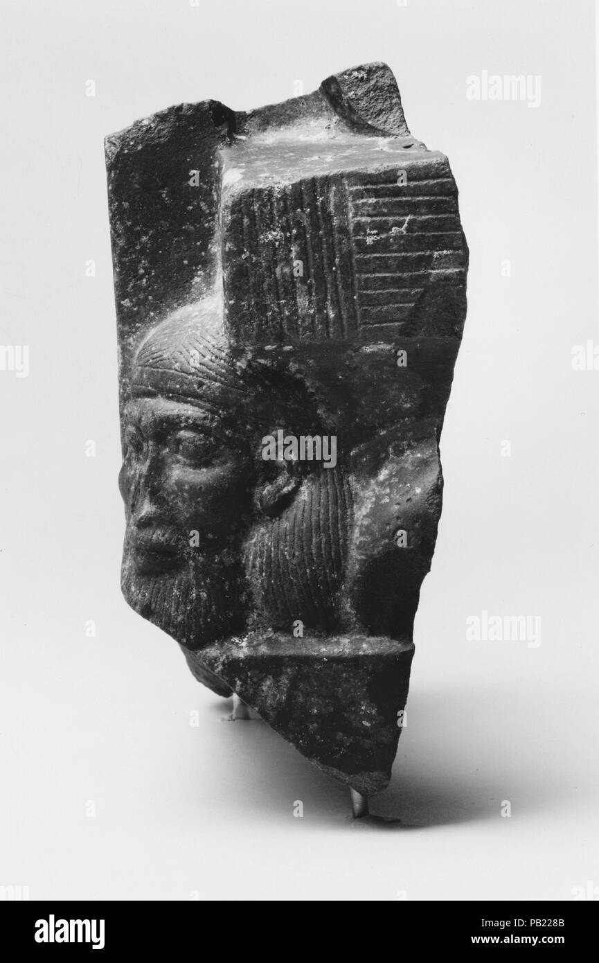 Fragment of a sculptured statue base depicting an Asiatic prisoner. Dimensions: h. 21.6 cm (8 1/2 in); w. 11.4 cm (4 1/2 in); d. 18 cm (7 1/16 in). Dynasty: Dynasty 19. Reign: reign of Ramesses I-Seti I. Date: ca. 1300-1250 B.C..  Ancient Egyptian artists expressed the might of the pharaoh through a variety of images. One of these is the image of the pharaoh standing or enthroned above the bodies of foreigner captives.   This fragment of a statue base shows the head and shoulder of a Syrian who is characterized by long strands of hair confined by a headband, a beard and mustache, and a fringed Stock Photo
