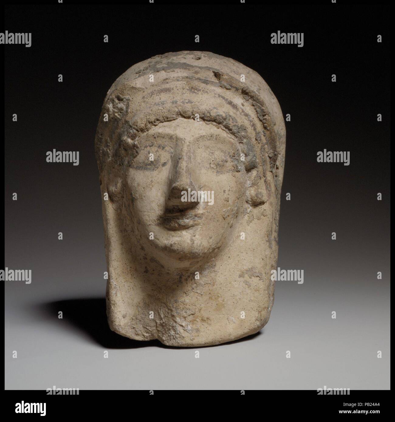 Female protome-mask. Culture: Cypriot. Dimensions: H. 5 5/16 in. (13.5 cm). Date: end of the 6th century B.C..  The protome-mask is mold-made. It has a pointed nose, a prominent chin, large eyes, and ridged eyebrows. A fringe of curly hair frames the forehead. A ridge above and separated from the hair by a band is probably the edge of a veil. Museum: Metropolitan Museum of Art, New York, USA. Stock Photo
