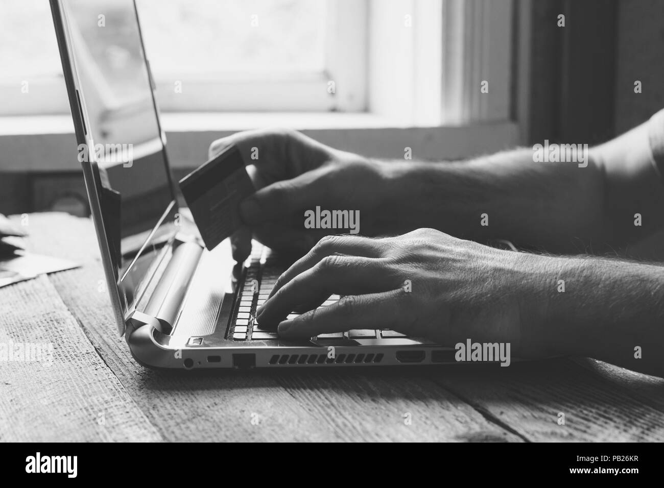 Man Hands holding credit card and using laptop in the evening. Online shopping, online banking and online marketing. shallow depth of field, black and Stock Photo