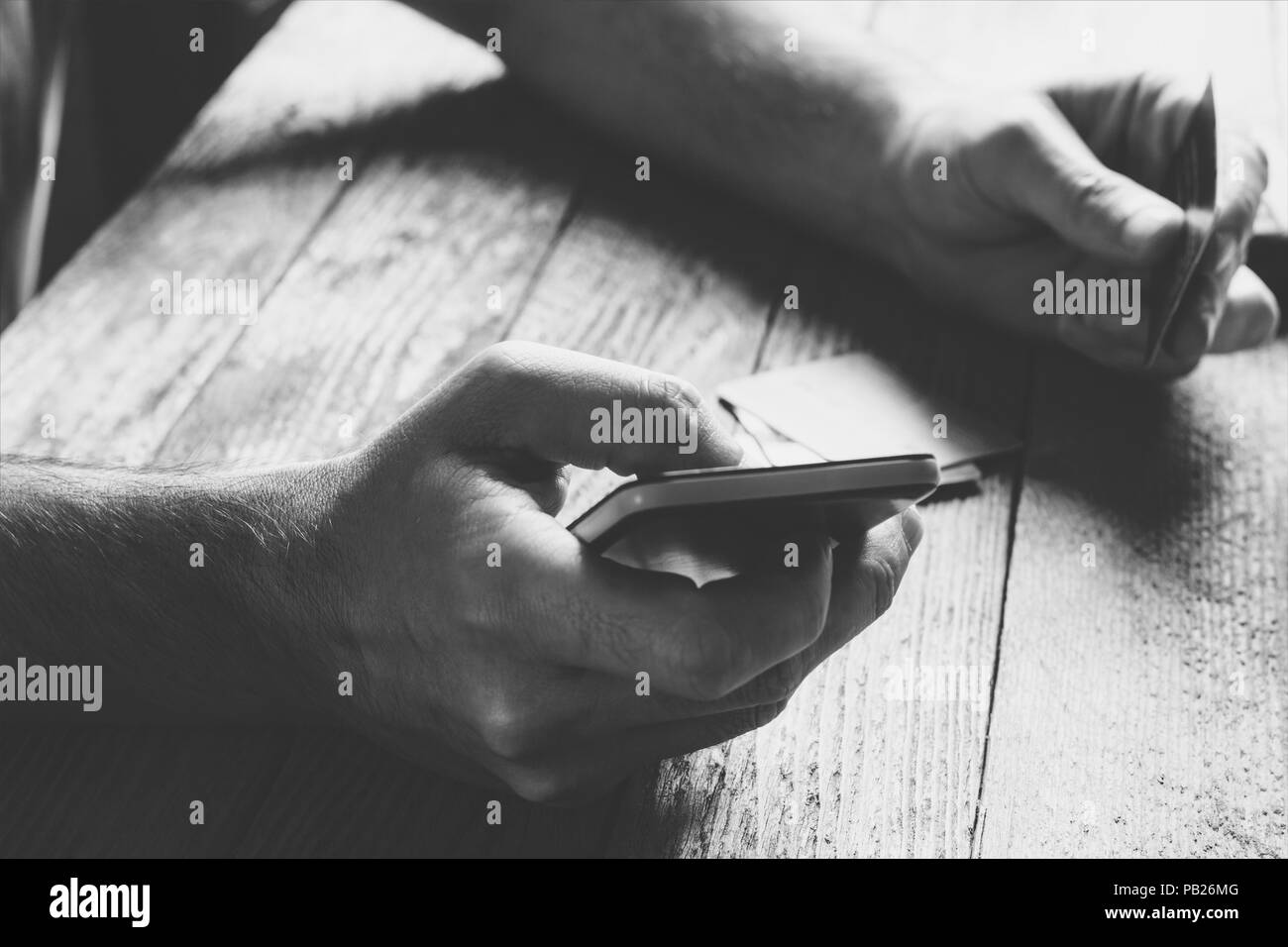 Man Hands holding credit card and using mobile phone in the evening. Online shopping, online banking and online marketing. shallow depth of field,  bl Stock Photo