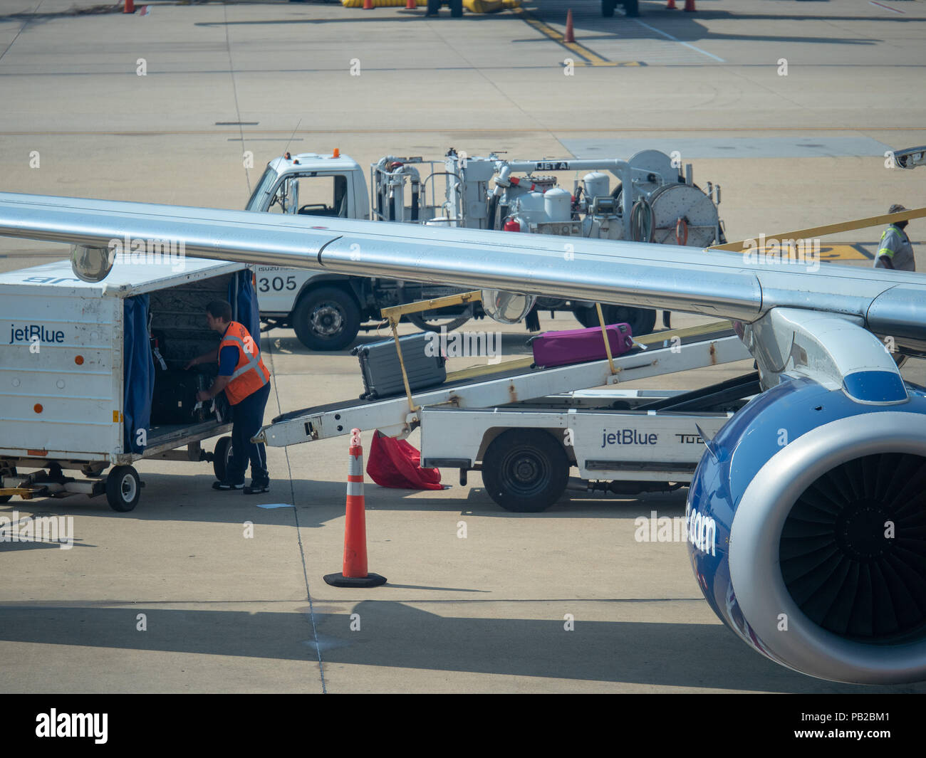 jetBlue baggage handler loading luggage into an airliner at Reagan