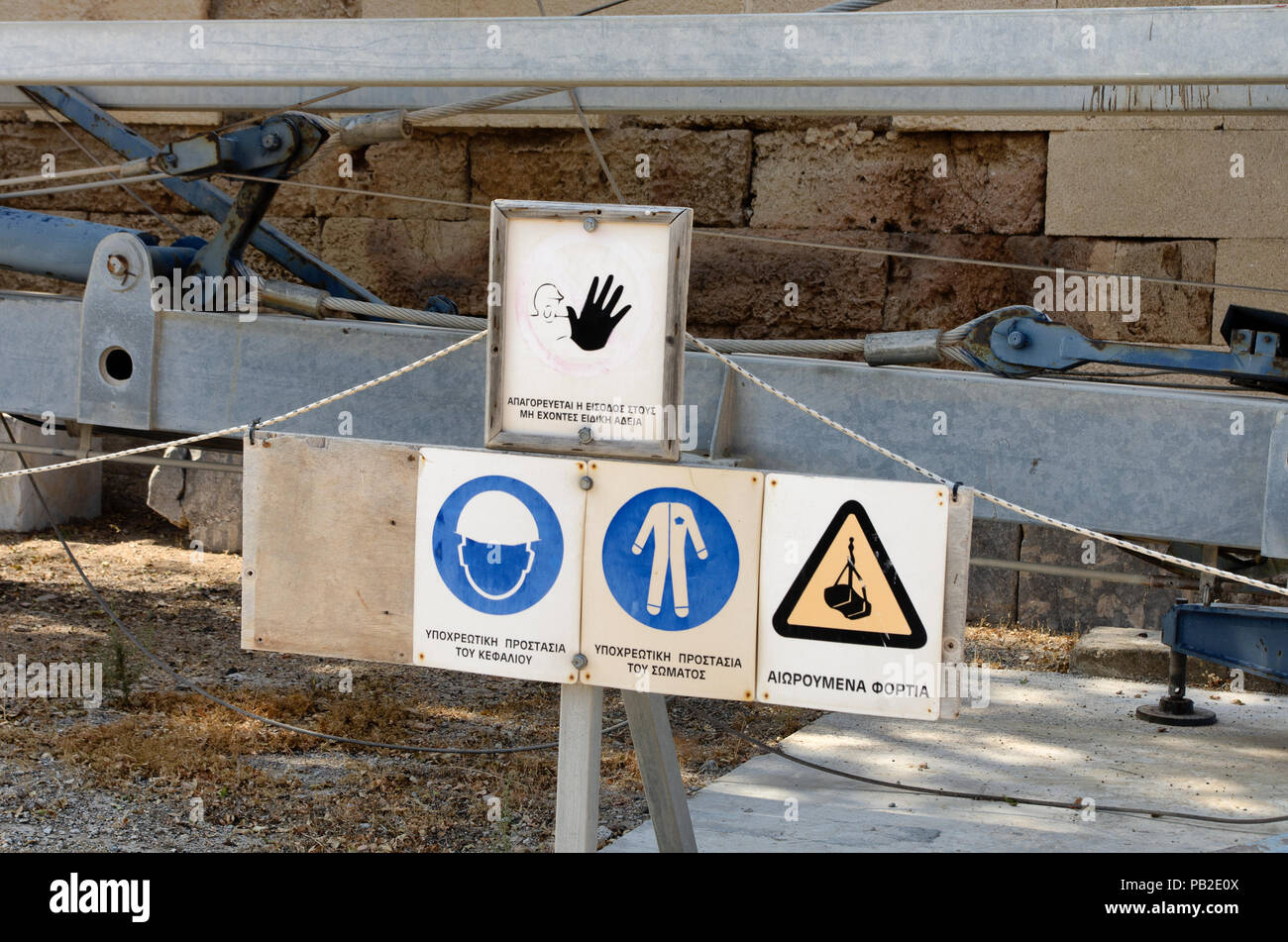 Construction safety signs with inscriptions in the Greek language ('Forbidden to enter without special permission, 'Mandatory head protection', 'Manda Stock Photo