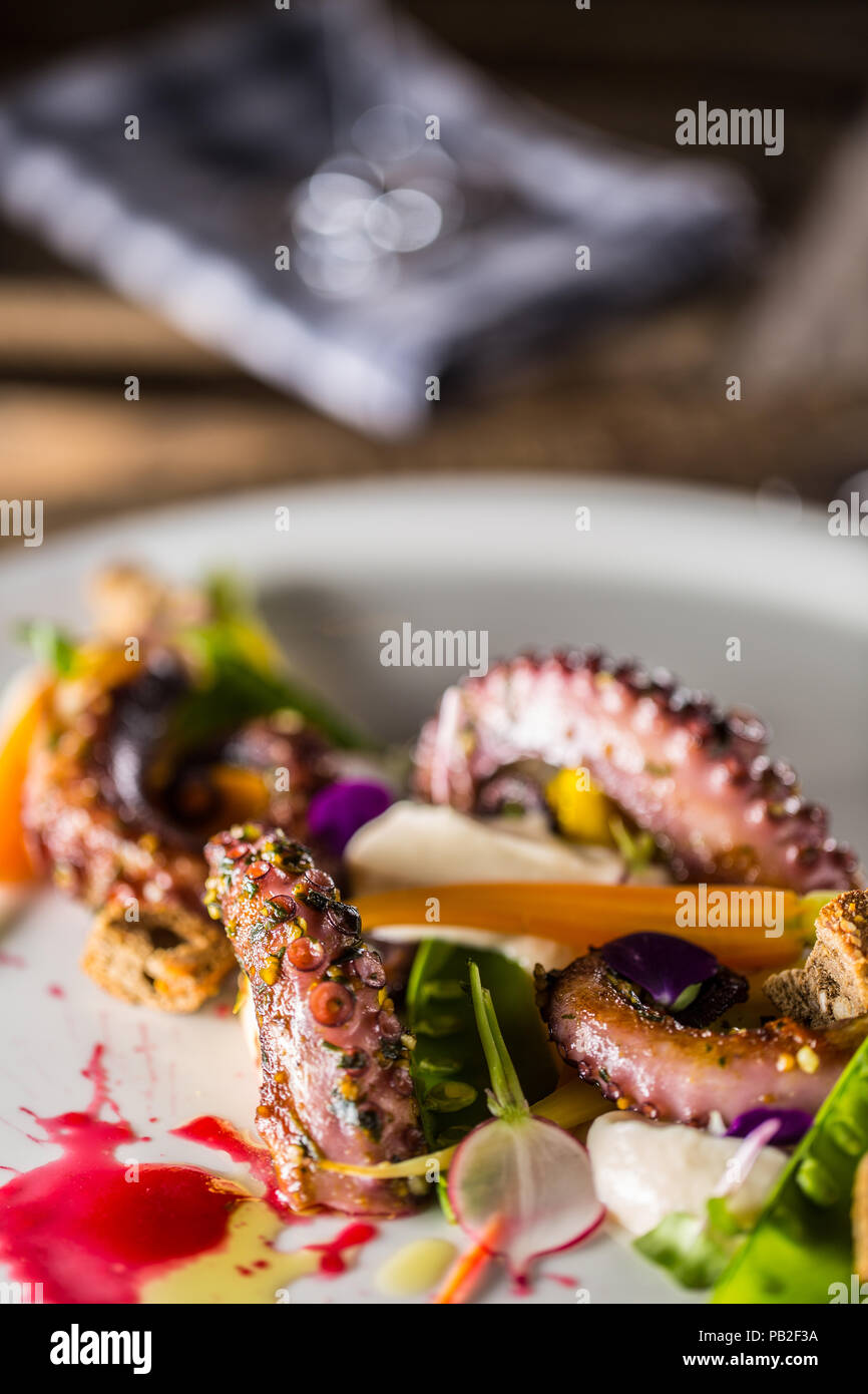 Octopus with vegetable salad on white plate with aperitif. Culinary