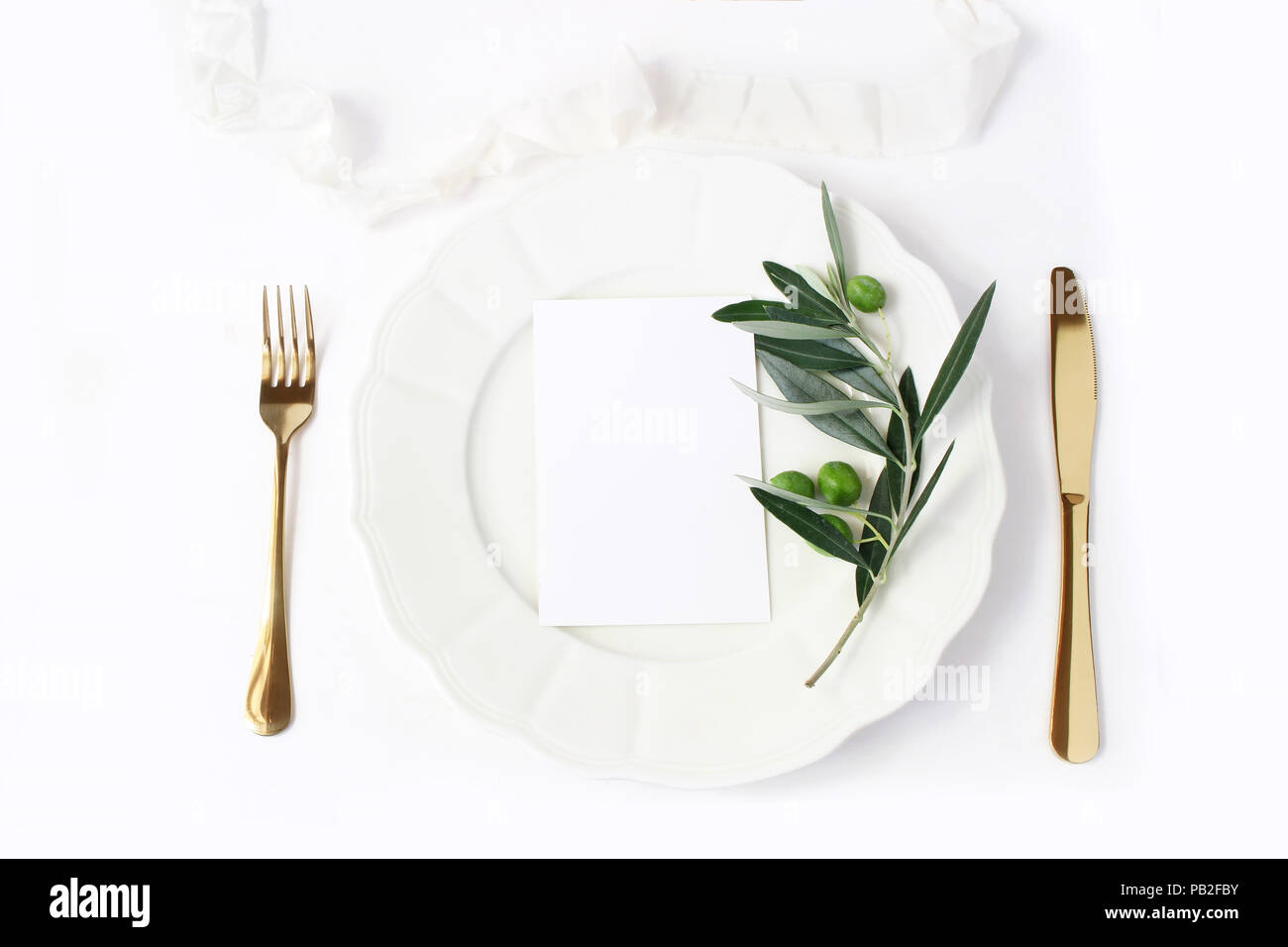 Festive table summer setting with golden cutlery, olive branch, porcelain dinner  plate and silk ribbon on white table background. Blank card mockup, M Stock  Photo - Alamy
