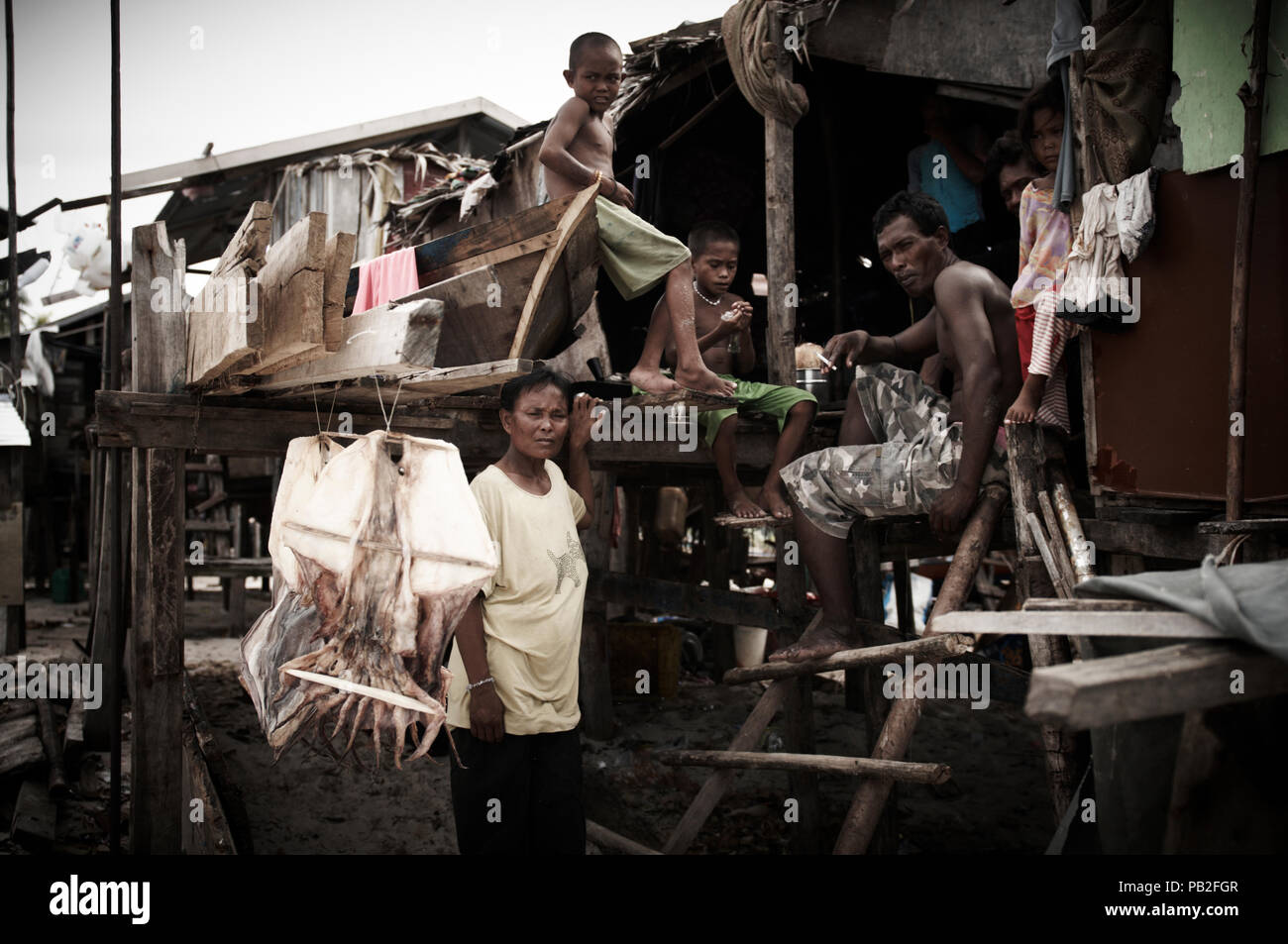 A Bajau family of 14 live on Mabul Island illegally. Their catch of squid for the day dries in the sun for dinner later on.  Too large a group to live on a boat the family now live on the island under threat of eviction at any time. There is no medical or educational support here for these families. - Stock Image