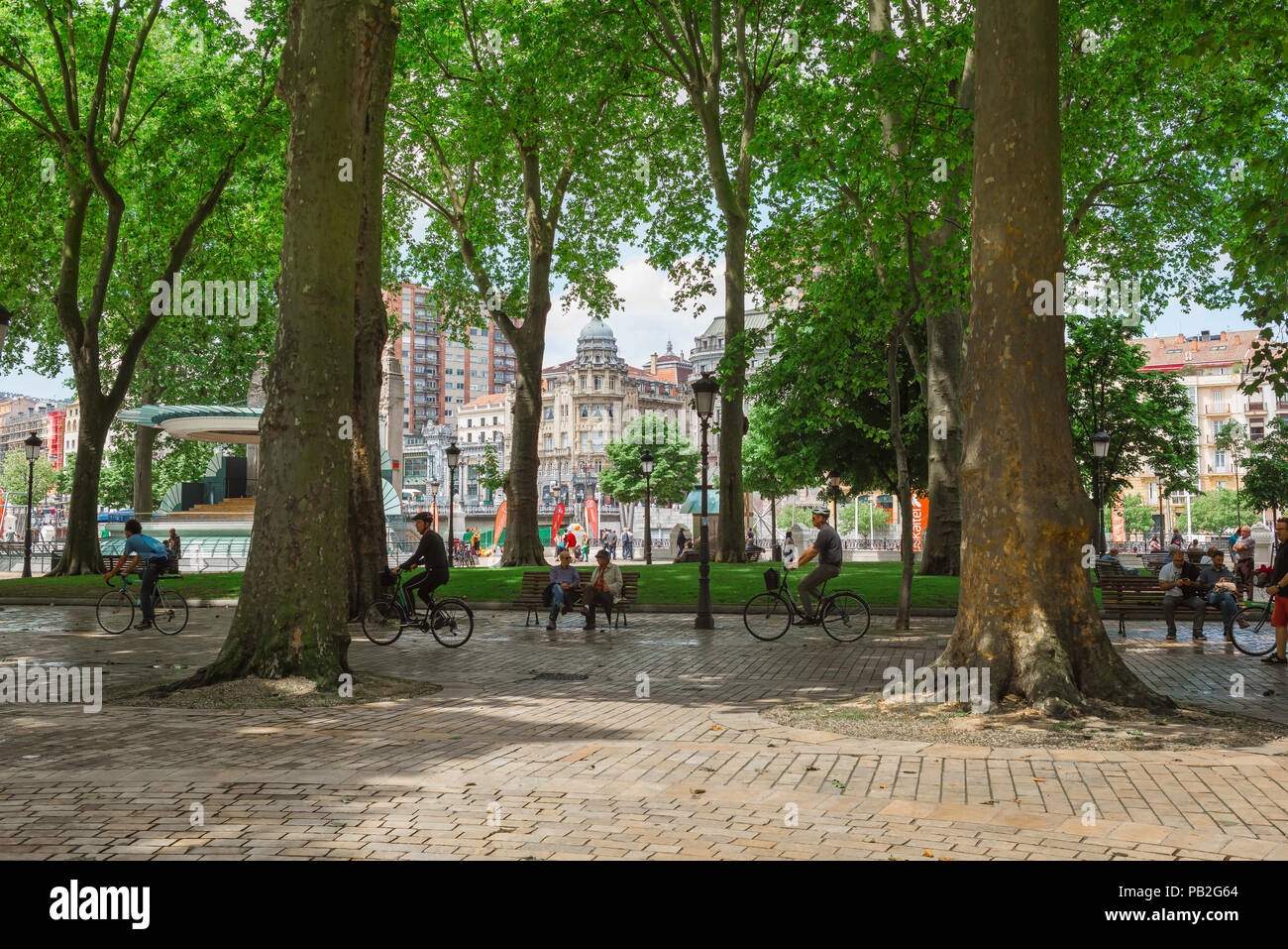 Bilbao park summer, view of people cycling through the tree-lined Paseo del Arenal in the center of Bilbao, Northern Spain. Stock Photo
