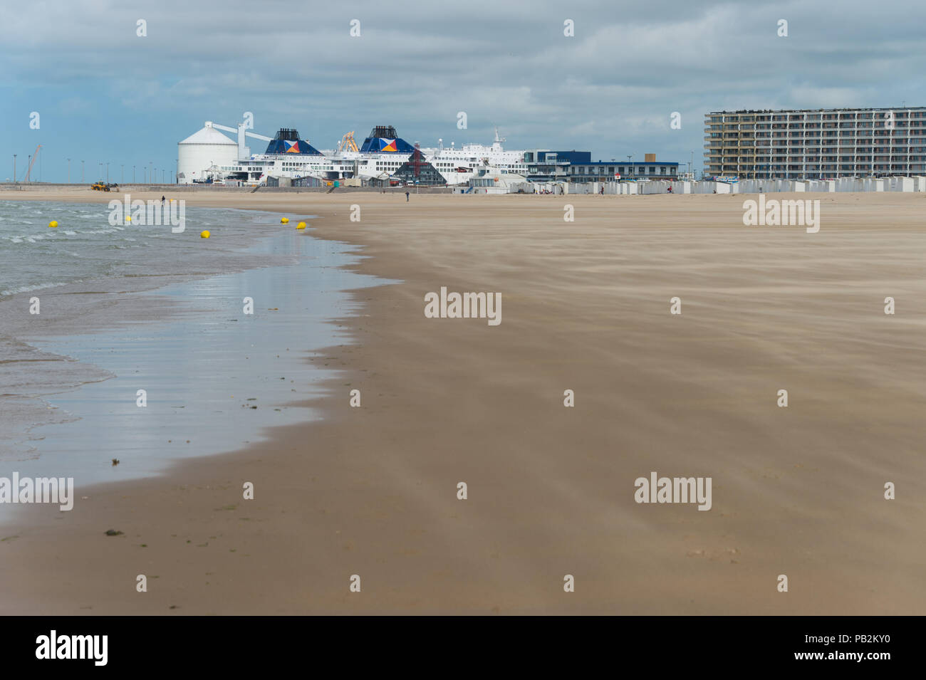 Calais, France - 19 June 2018: Beach at low tide in summer and ferry docked in the harbor. Stock Photo