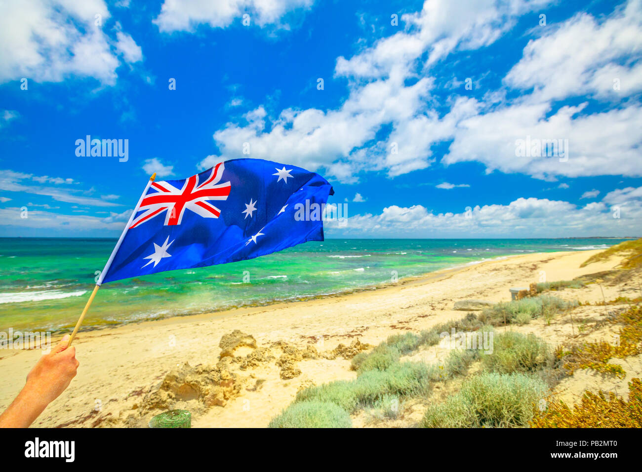 Australian flag waving on the foreground with coastal landscape of Mettams Pool, Trigg Beach, North Beach near Perth in Western Australia. Tourism in Australia. Stock Photo