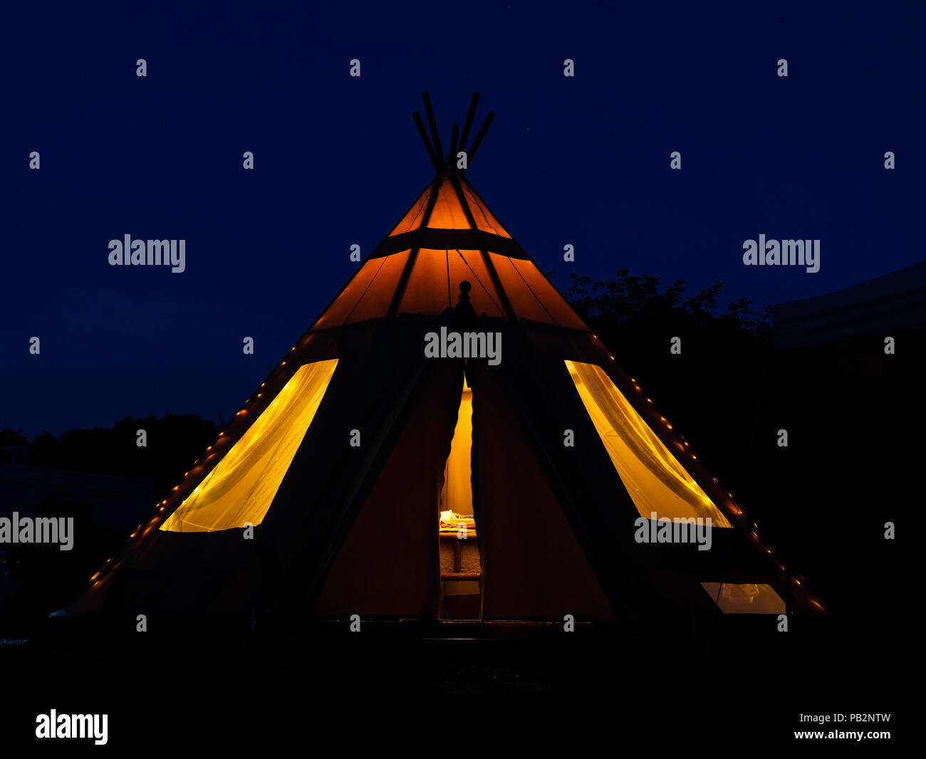 An image of a tipi teepee  taken in the evening, lit up with interior lights Stock Photo