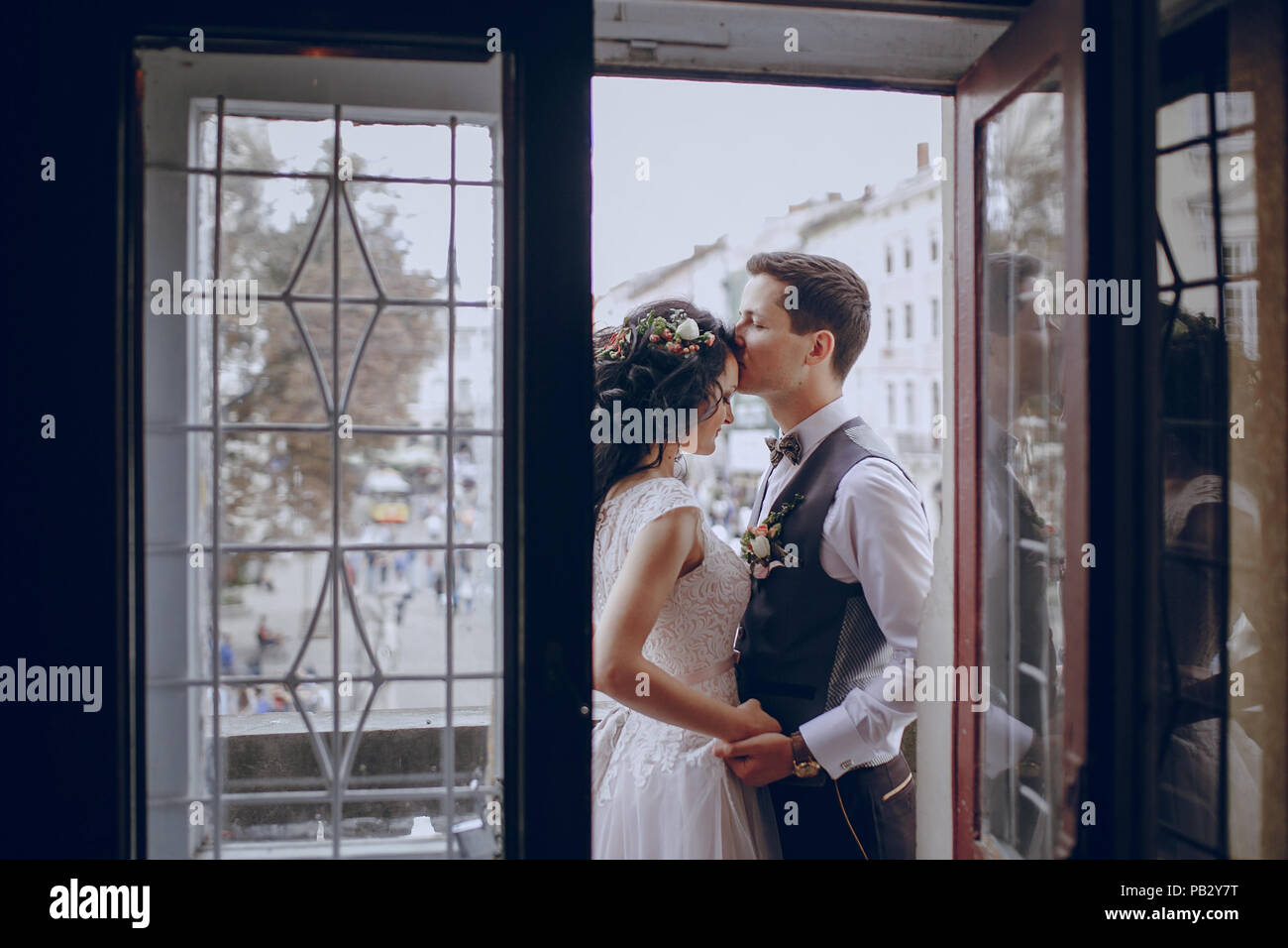 bride and groom standing by the window and kissing Stock Photo - Alamy