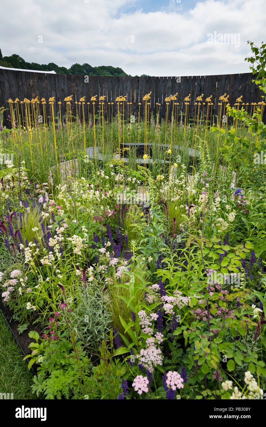 Beautiful show garden (natural planting, colourful meadow flowers, tractor sculpture) - John Deere Garden, RHS Chatsworth Flower Show, England, UK. Stock Photo