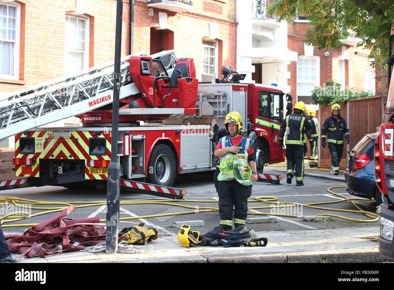 Fire crew outside a block of flats on Inglewood Road, north west London, after 100 firefighters were called to put out the blaze just after 1am on Thursday. Stock Photo