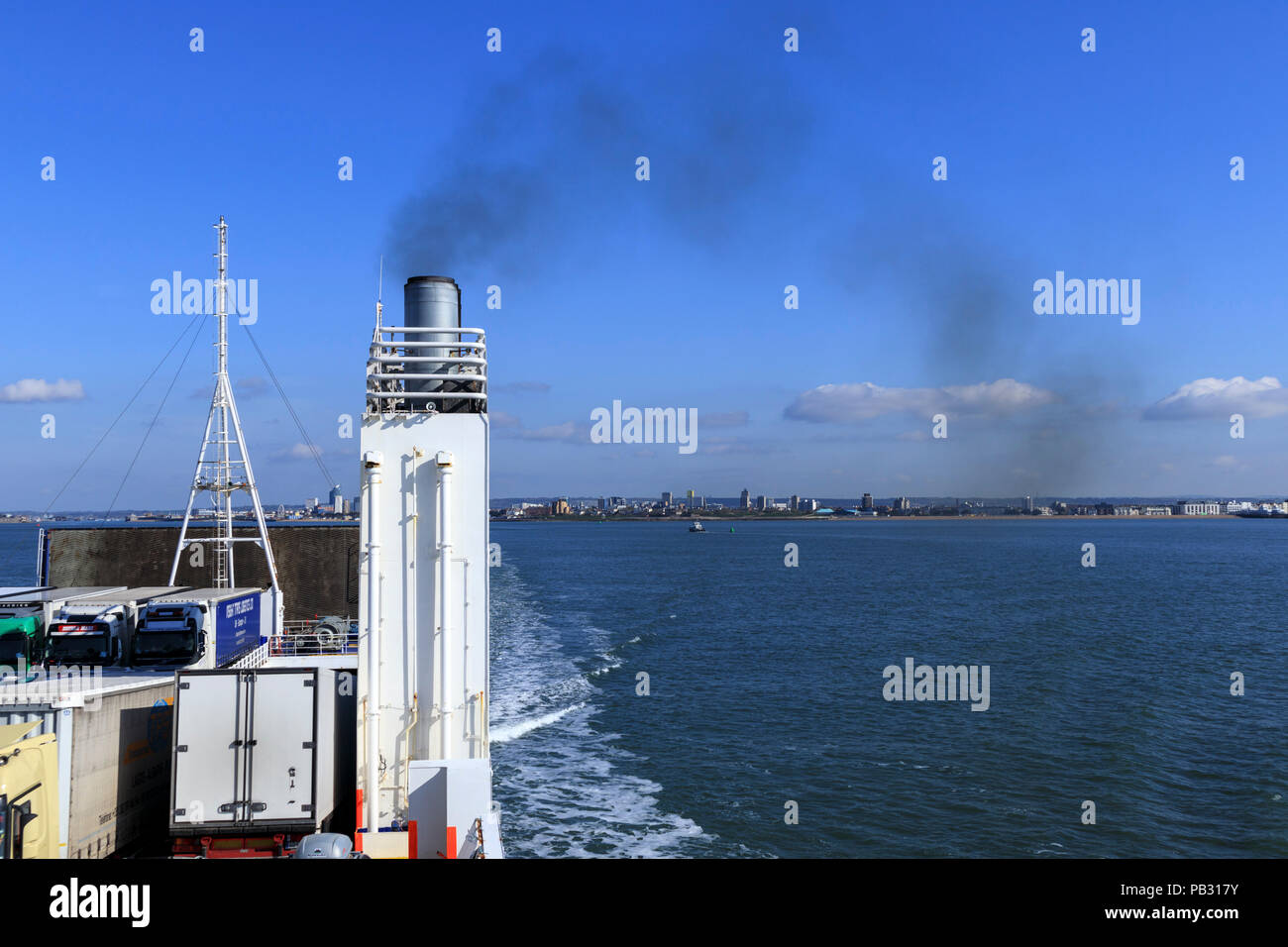 Black smoke trailing from a ferry funnel polluting the atmosphere against a blue sky Stock Photo
