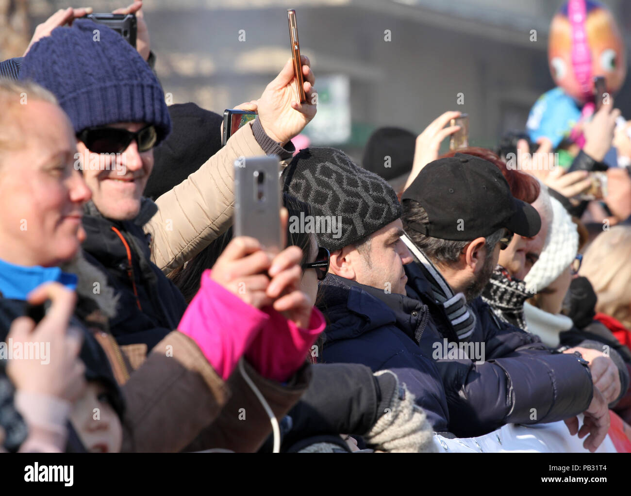 A crowd of people use different types of smart phones and tablets to take a pictures of interesting things . Many phones in one place. smart devices a Stock Photo