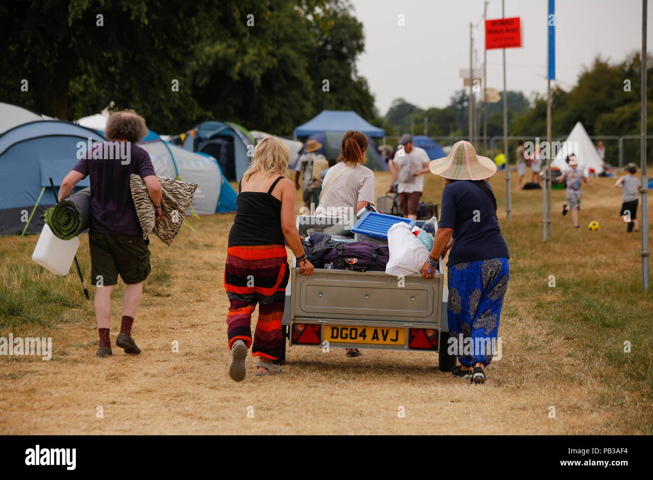 Charlton Park, Malmesbury, Wiltshire. 26th July 2018. In record breaking temperatures festival goers arrive to a sun baked and scorched WOMAD festival site for the 36th annual festival of World music, arts and dance. The public are in good spirits and haul in a crazy array of different trailers and trollies piled high with camping equipment. Whilst some battle the heatwave to put up tents others retreat to the leafy arboretum to find shade and snooze amongst the trees and colourful stalls. Credit: Wayne Farrell/Alamy Live News Stock Photo