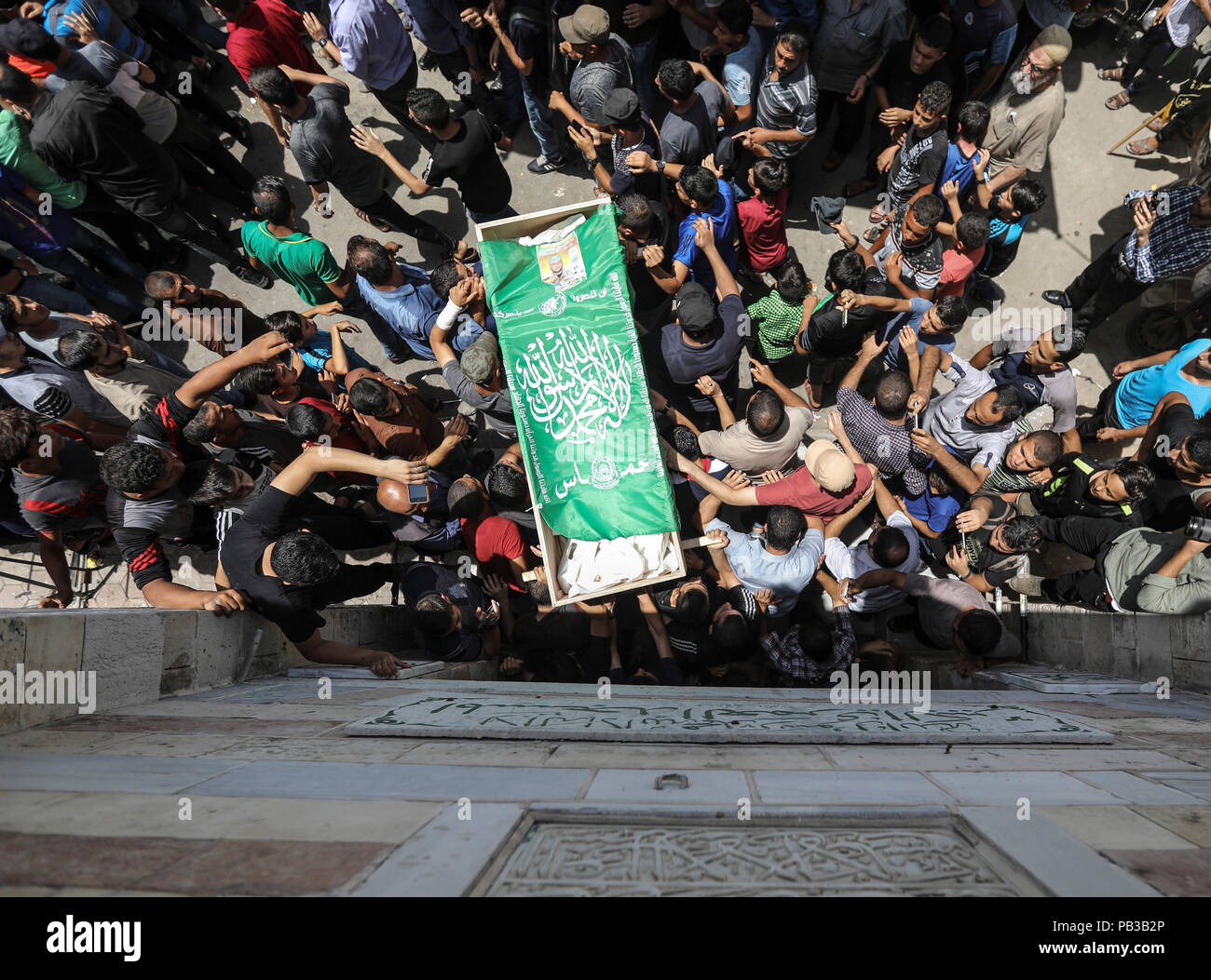 26 July 2018, Palestinian Autonomous Territories, Gaza: Palestinian mourners carry the body of a Kassam brigade fighter killed the day before in Israeli attacks in the coastal strip during his funeral. A few days after a ceasefire was announced, the situation in Gaza has escalated again. Photo: Wissam Nassar/dpa Stock Photo