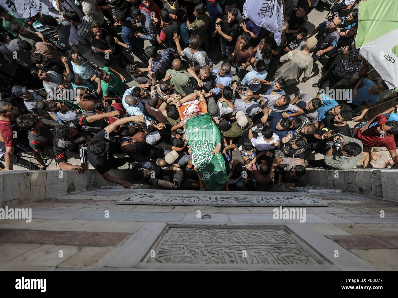 26 July 2018, Palestinian Autonomous Territories, Gaza: Palestinian mourners carry the body of a Kassam brigade fighter killed the day before in Israeli attacks in the coastal strip during his funeral. A few days after a ceasefire was announced, the situation in Gaza has escalated again. Photo: Wissam Nassar/dpa Stock Photo