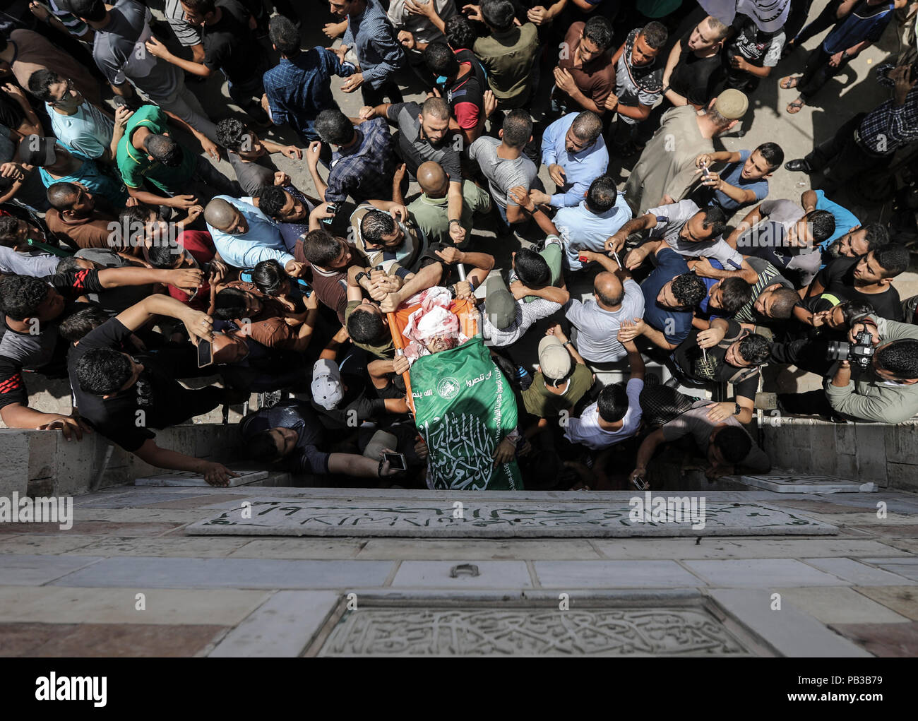 26 July 2018, Palestinian Autonomous Territories, Gaza: Palestinian mourners carry the body of a Kassam brigade fighter killed the day before in Israeli attacks in the coastal strip during his funeral. A few days after a ceasefire was announced, the situation in Gaza has escalated again. Photo: Wissam Nassar/dpa Stock Photo