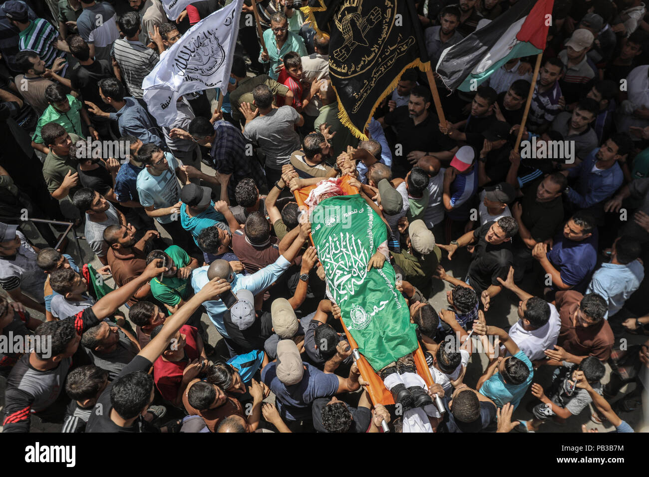 26 July 2018, Palestinian Autonomous Territories, Gaza: Palestinian mourners carry the body of a Kassam brigade fighter killed the day before in Israeli attacks in the coastal strip during his funeral. A few days after a ceasefire was announced, the situation in Gaza has escalated again. Photo: Wissam Nassar/dpa Stock Photo