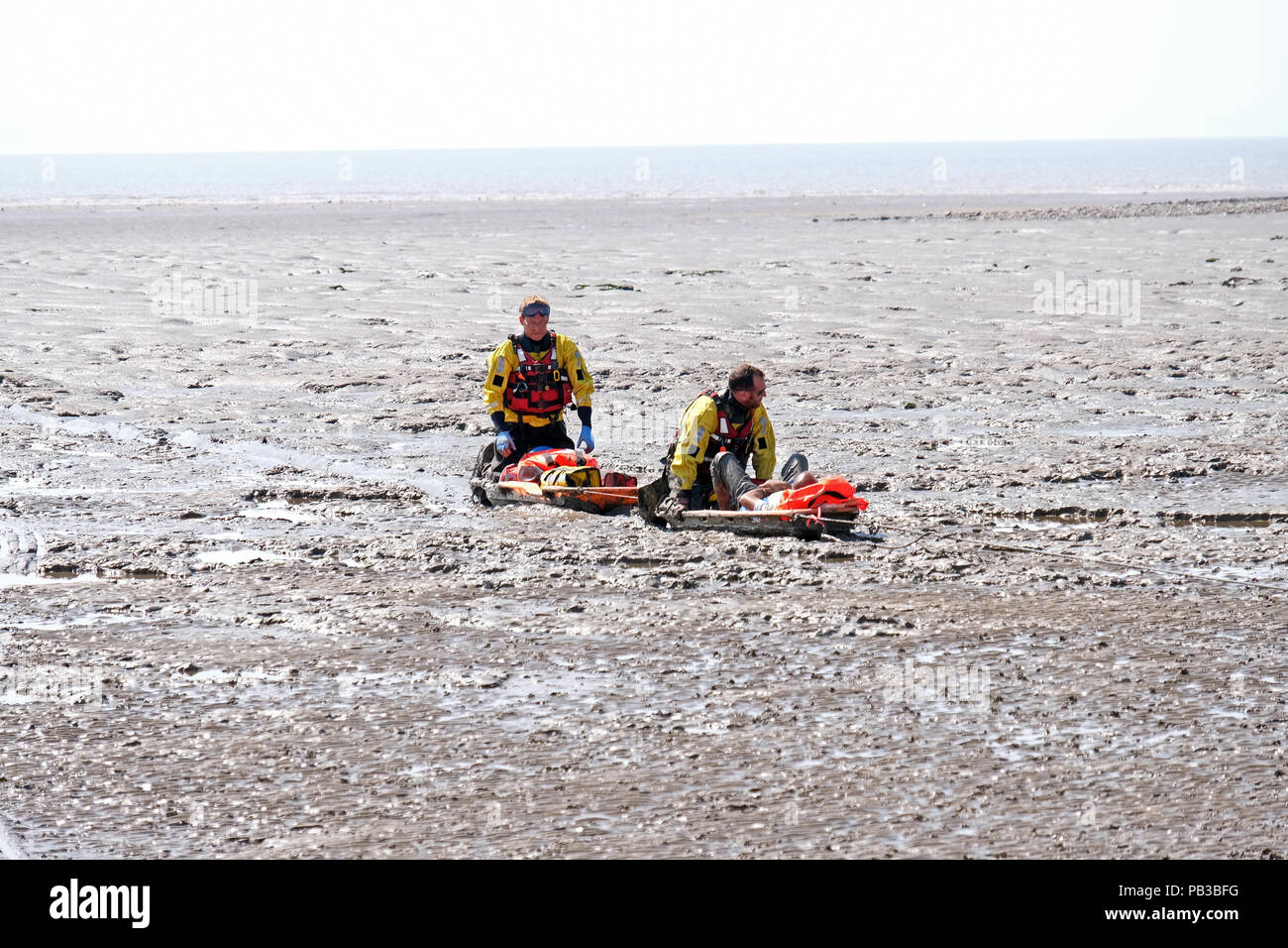 Weston-super-Mare, UK. 26th July, 2018. Coastguards rescue a man who had become trapped on the mud flats below the beach. Weston-super-Mare is situated on the Severn estuary, which has the second-highest tidal range in the world, and people often become trapped in the large areas of dangerous soft mud which are exposed at low tide. Keith Ramsey/Alamy Live News Stock Photo