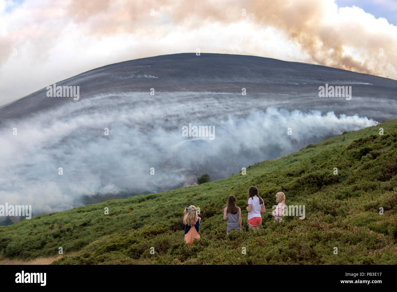 Public spectators watching the moorland fire at Llantysilio Mountain along the Horseshoe Pass, Llangollen as the fire burns over the mountain due to heatwave temperatures in the UK Stock Photo