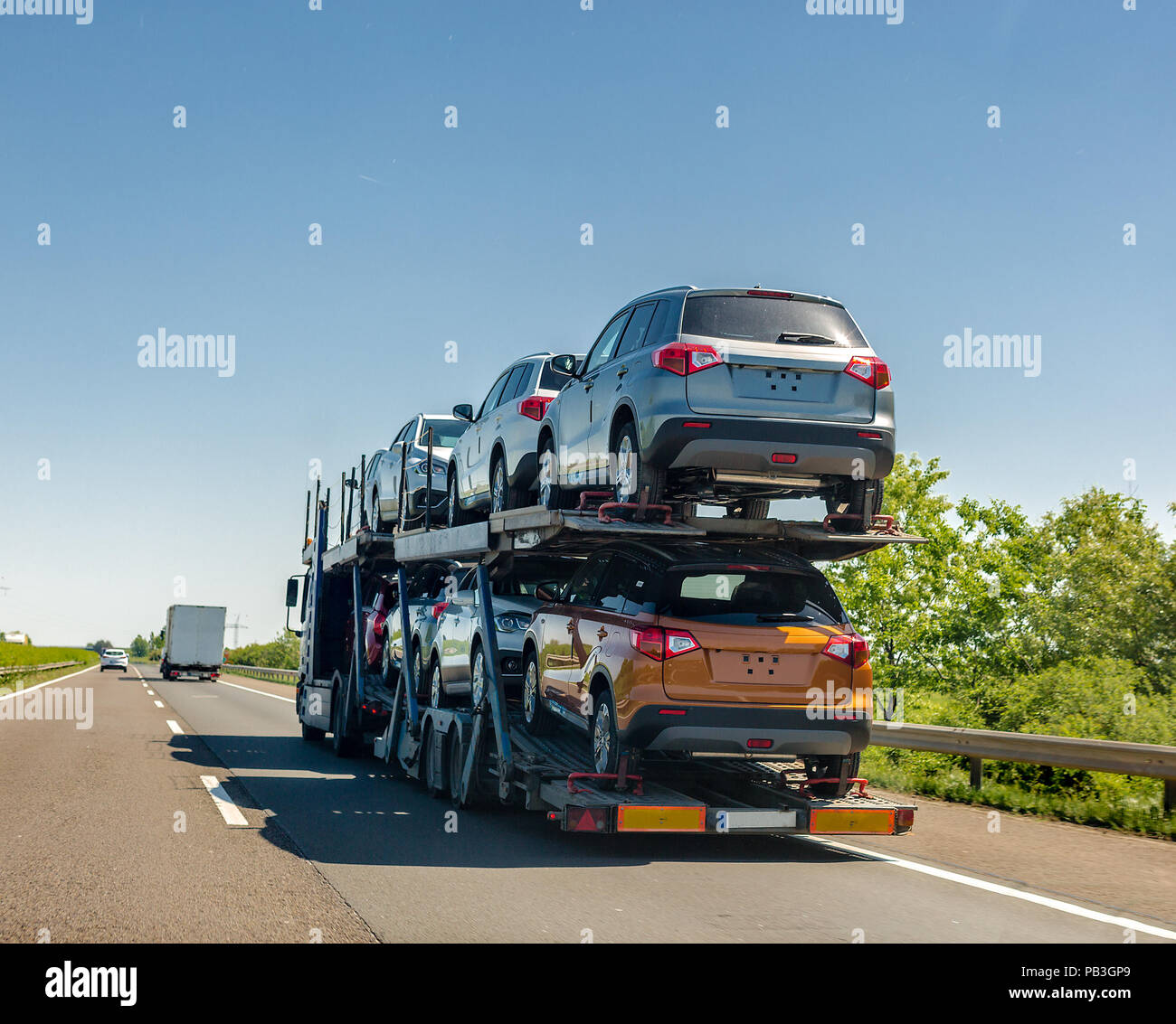 Car carrier trailer with new cars on bunk platform. Car transport truck on the highway Stock Photo