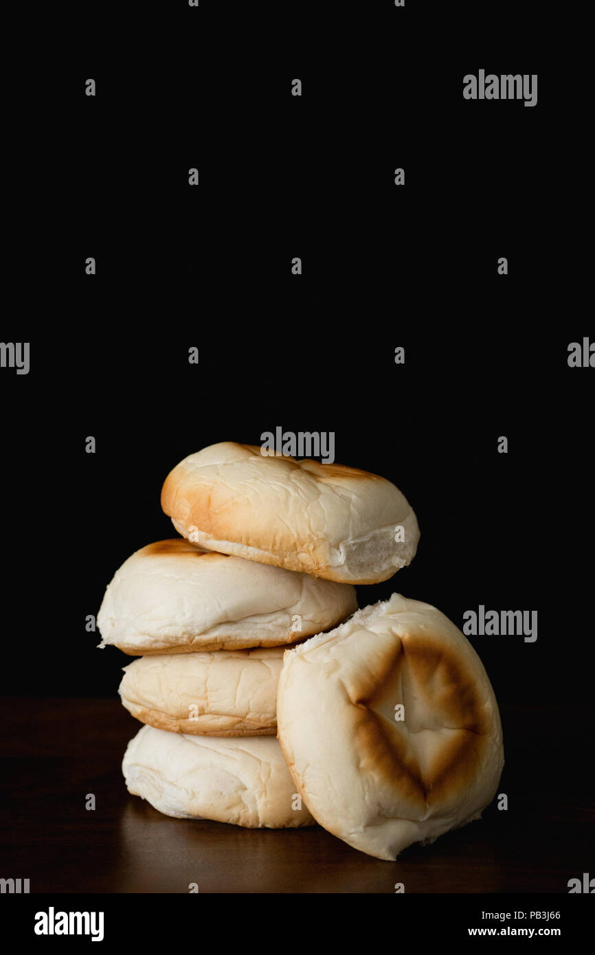 Still life. Five soft white bread rolls on a black background Stock Photo