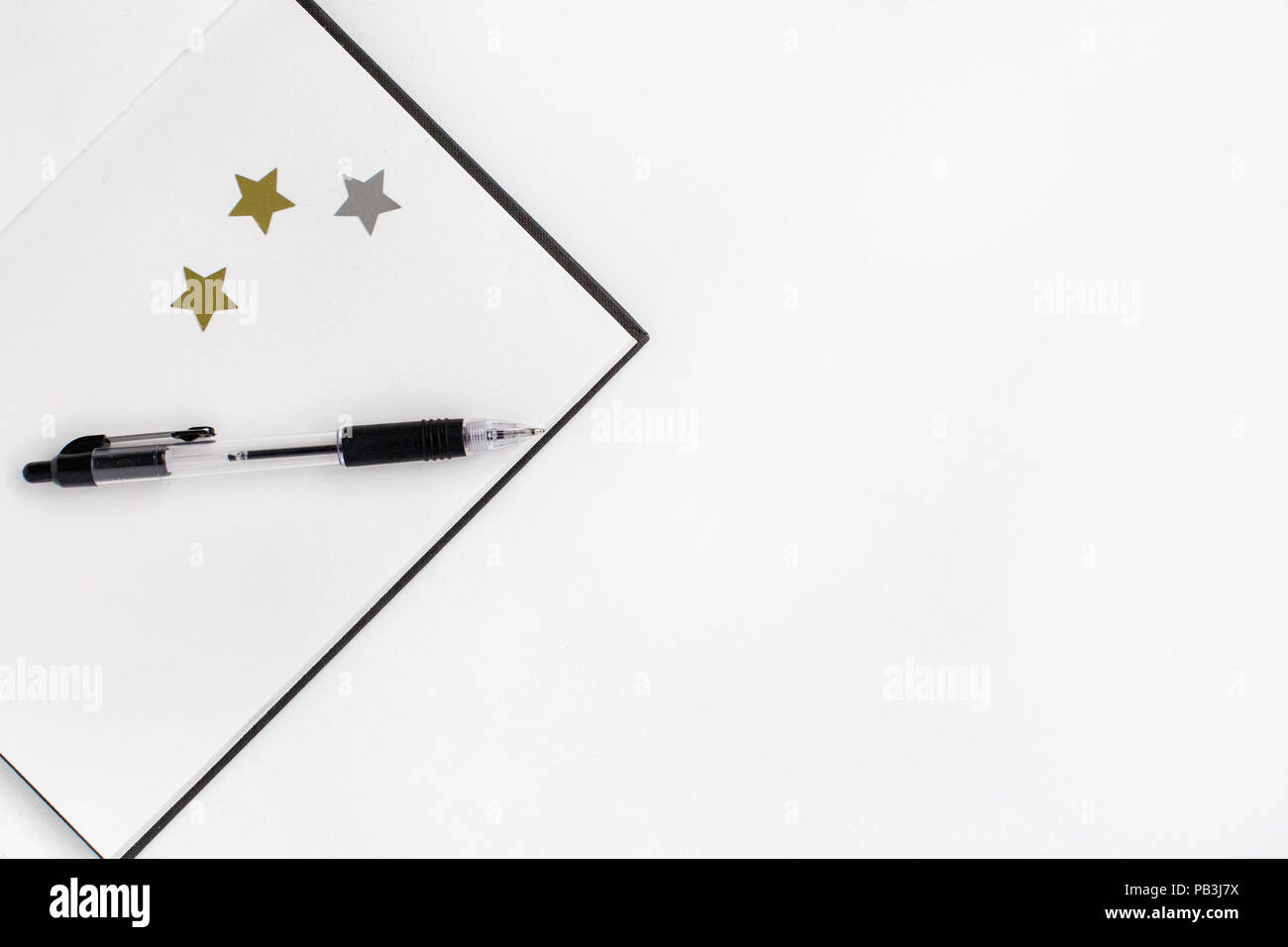 Flat lay of office desk with empty notebook, pen and stars on a white background Stock Photo