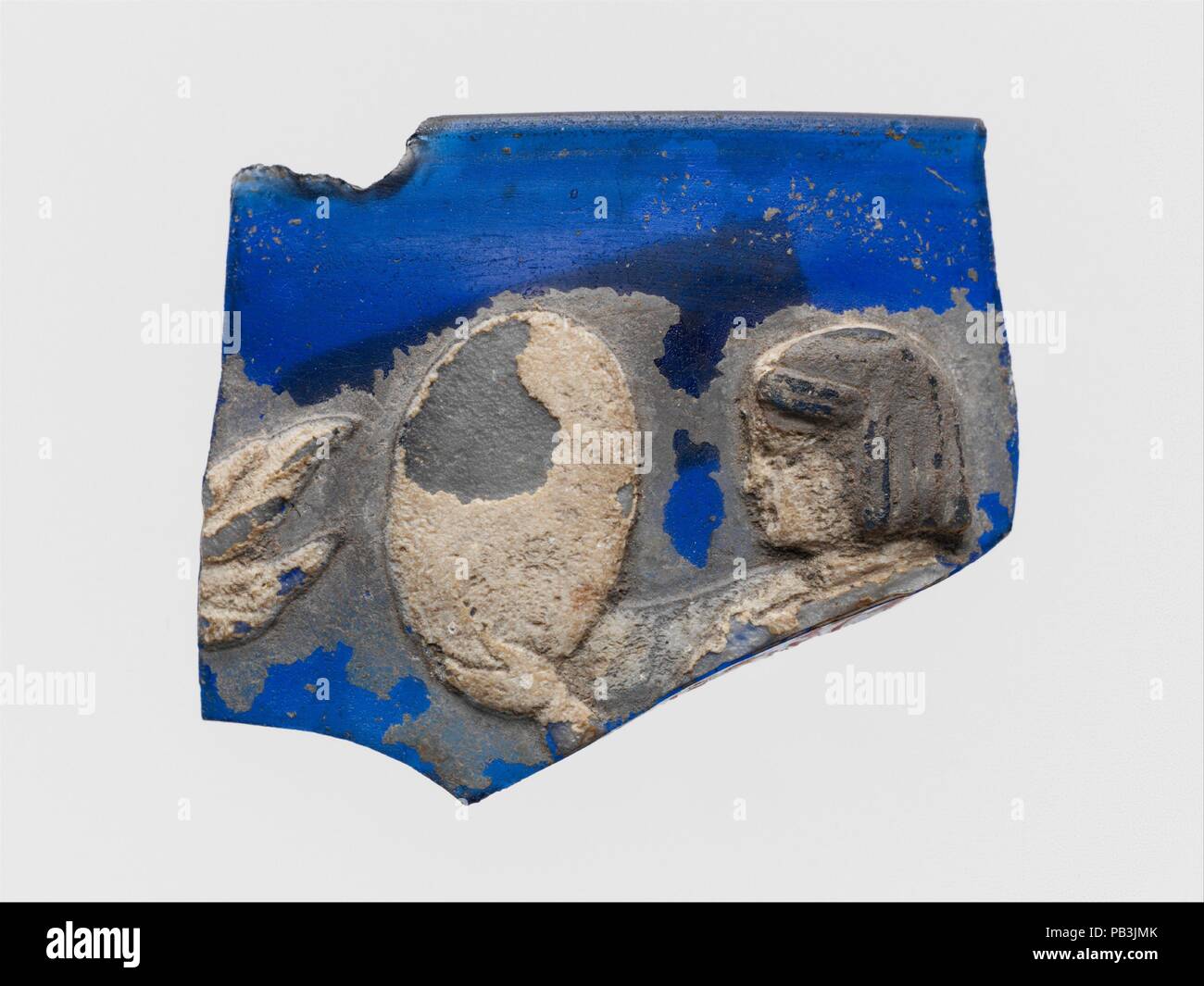 Glass cameo cup fragment. Culture: Roman. Dimensions: Overall: 1 1/4 x 1 7/16 in. (3.2 x 3.7 cm). Date: end of 1st century B.C-beginning of 1st century A.D..  Translucent cobalt blue with overlays in opaque white and translucent dark blue.  Vertical rim with everted lip and beveled inner edge; cylindrical body with slightly convex curving side.  On interior, horizontal groove below rim; on exterior, in relief female figure in white, probably standing, facing left and holding up in front of her in both hands a large oval object, perhaps a drum or tambourine; her head is in profile with her hair Stock Photo